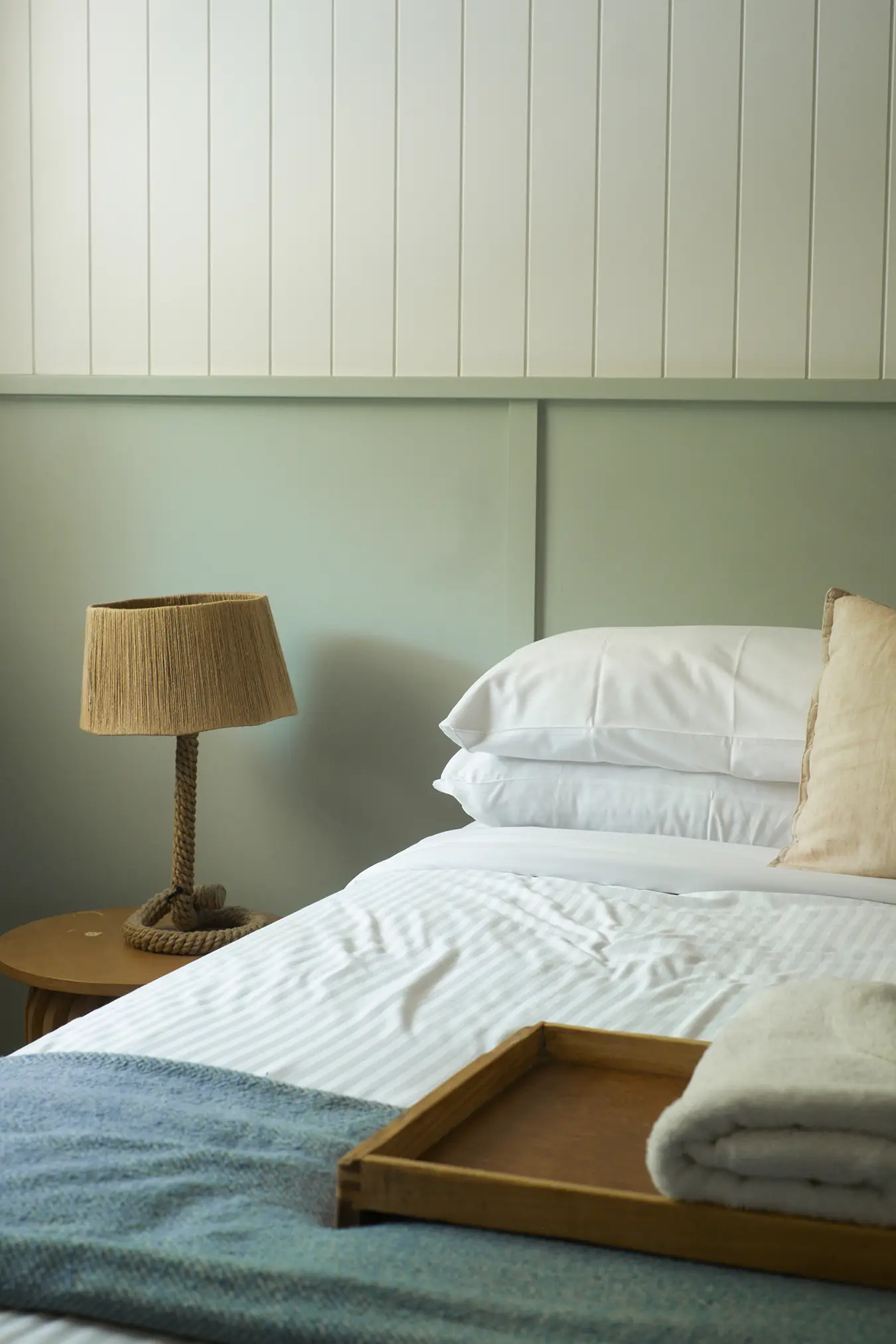 Bedside lamp and neatly made bed.