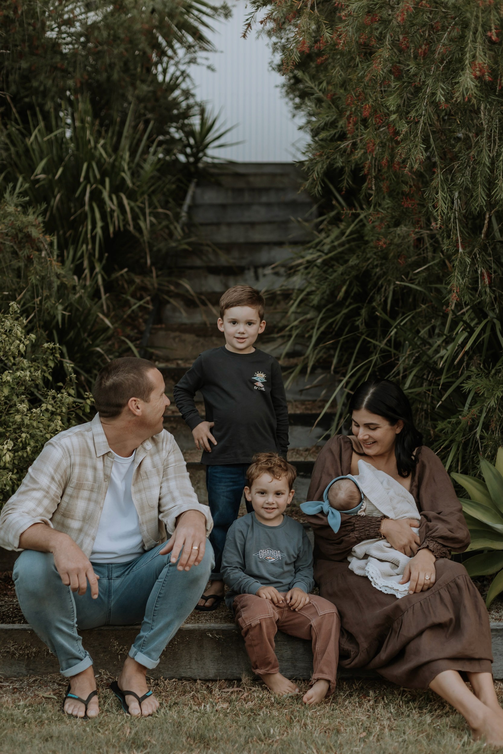 Mackay family photographer documenting mother and father embracing their children in golden hour light