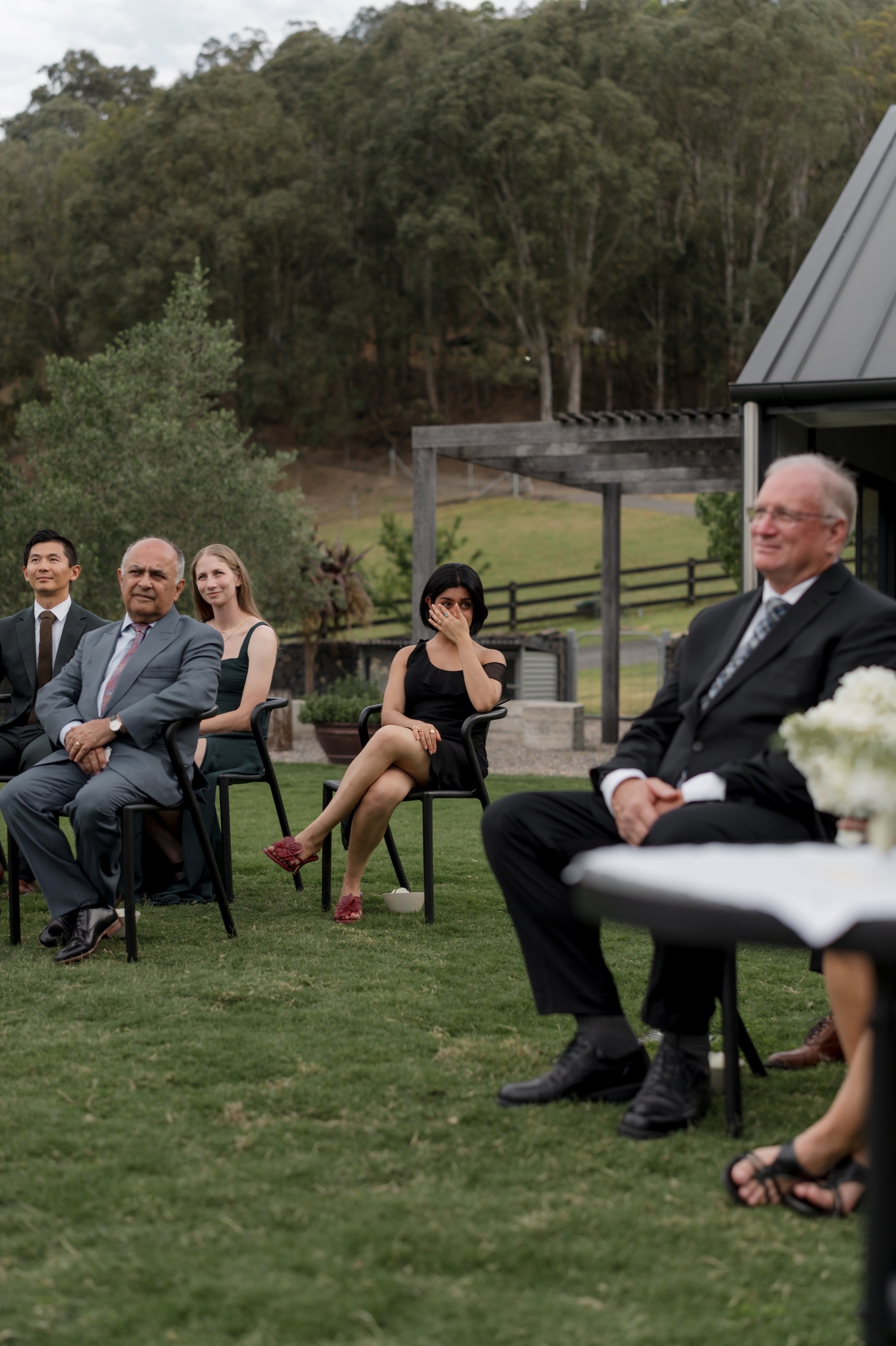 Wedding guest wiping away a tear during an outdoor ceremony