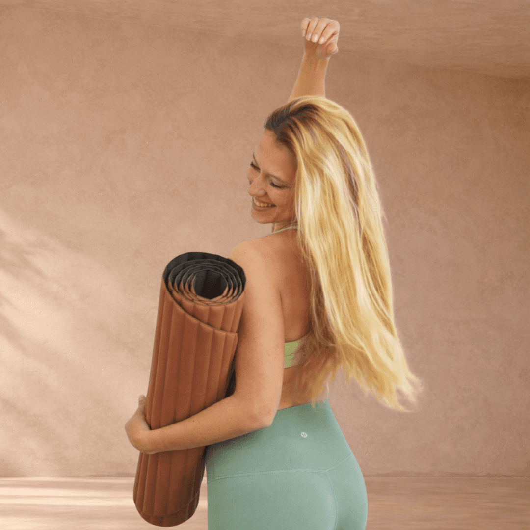 Woman with curly afro hair rests under palm leaf shadows.