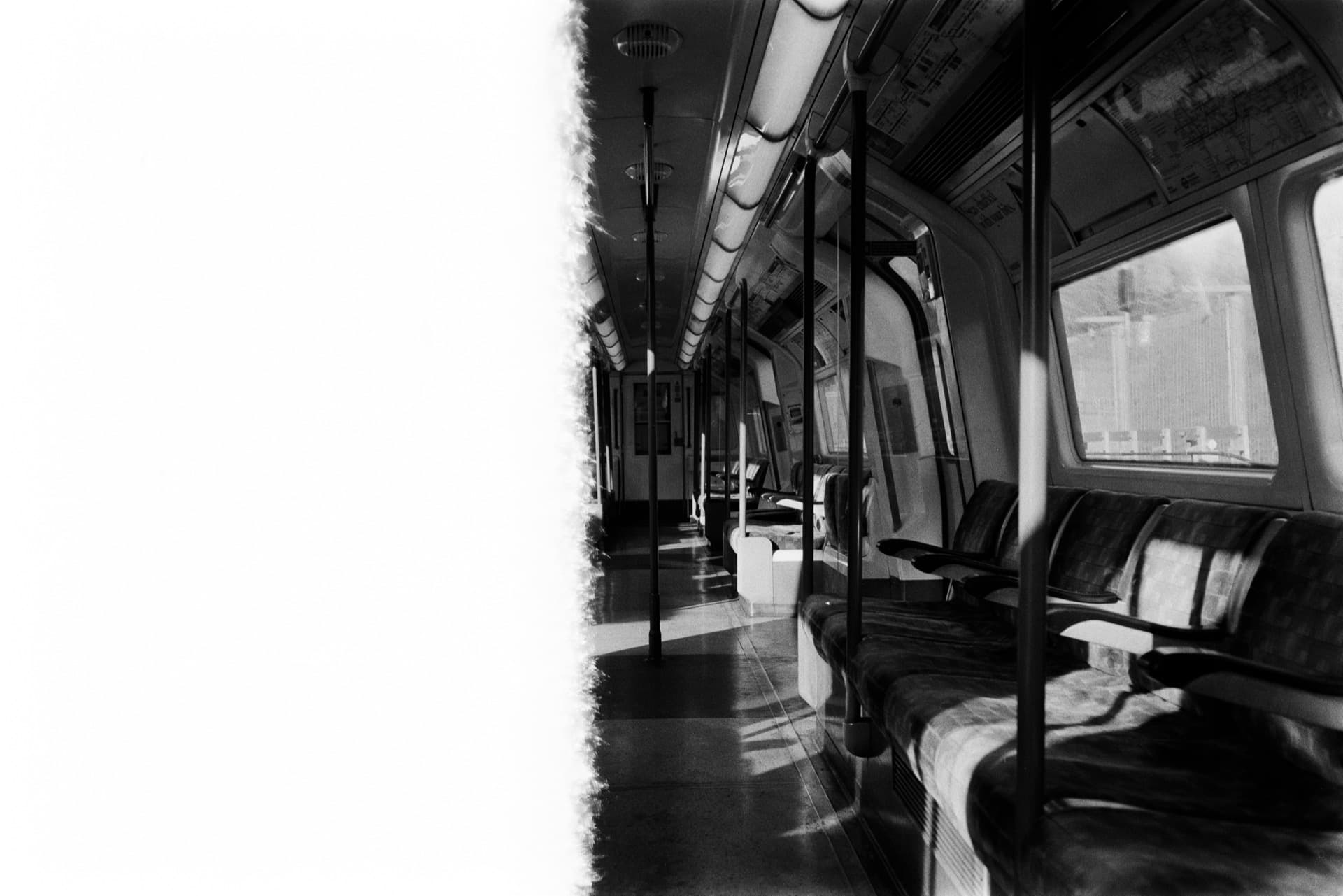 Empty London Underground train carriage interior with rows of seats and handrails