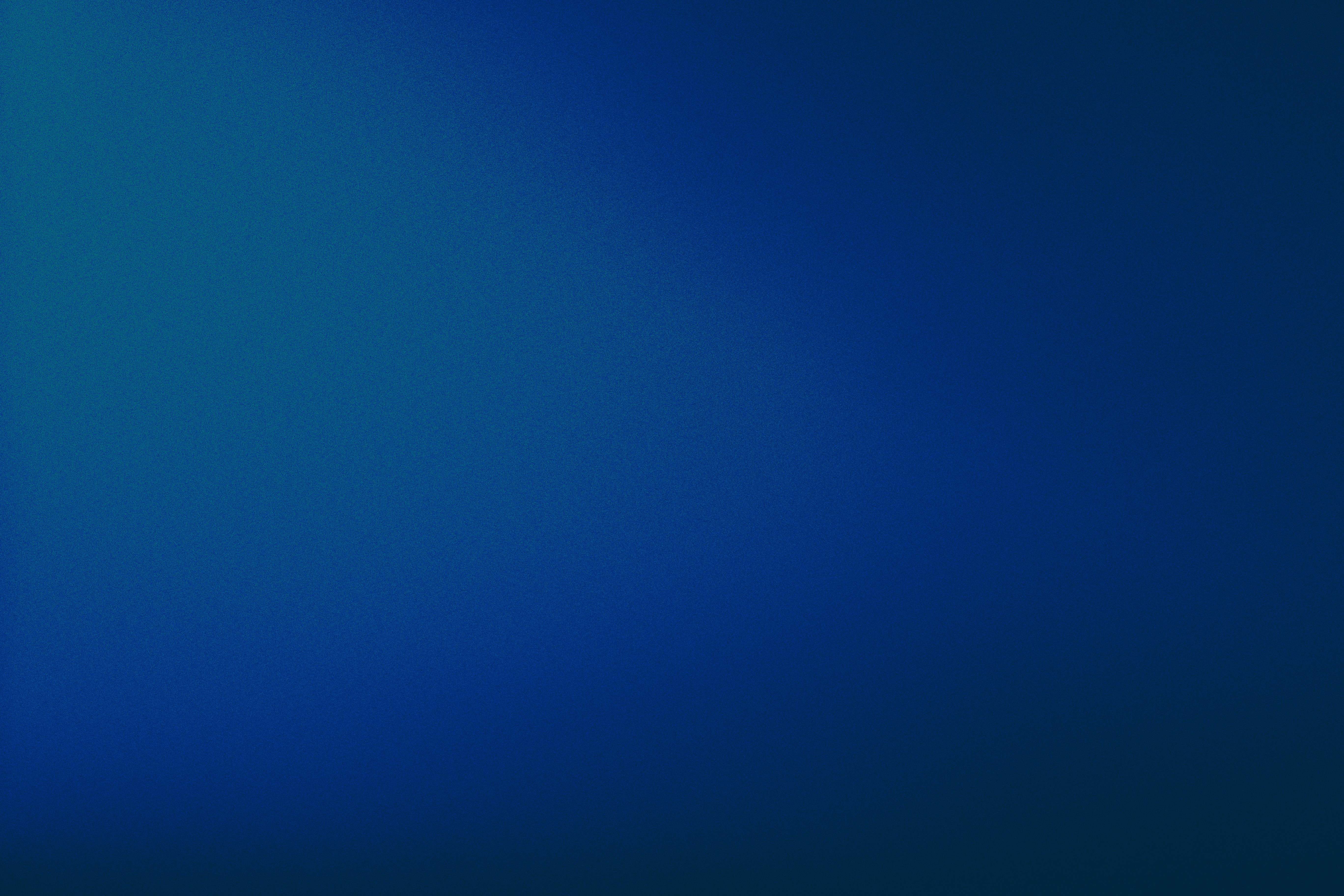 A man stands while two people sit at a table in an office setting, smiling and engaged in conversation. The mood is friendly and collaborative.