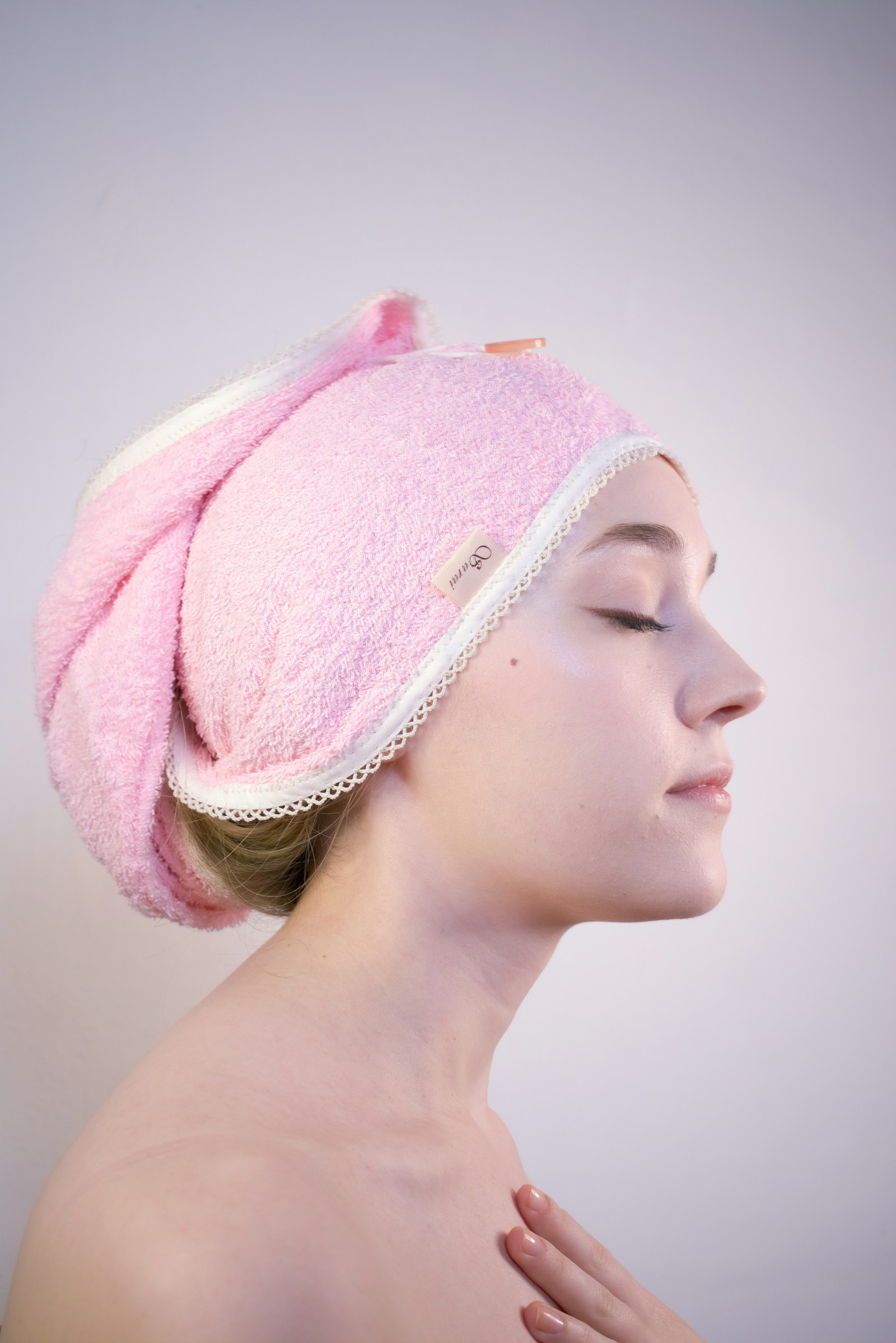 Woman with a pink towel wrapped around her hair, eyes closed