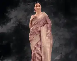 A woman wearing a peach tissue saree with a golden border from That Saree Shop, radiating a soft sheen and luxurious texture that captures timeless elegance and traditional charm.