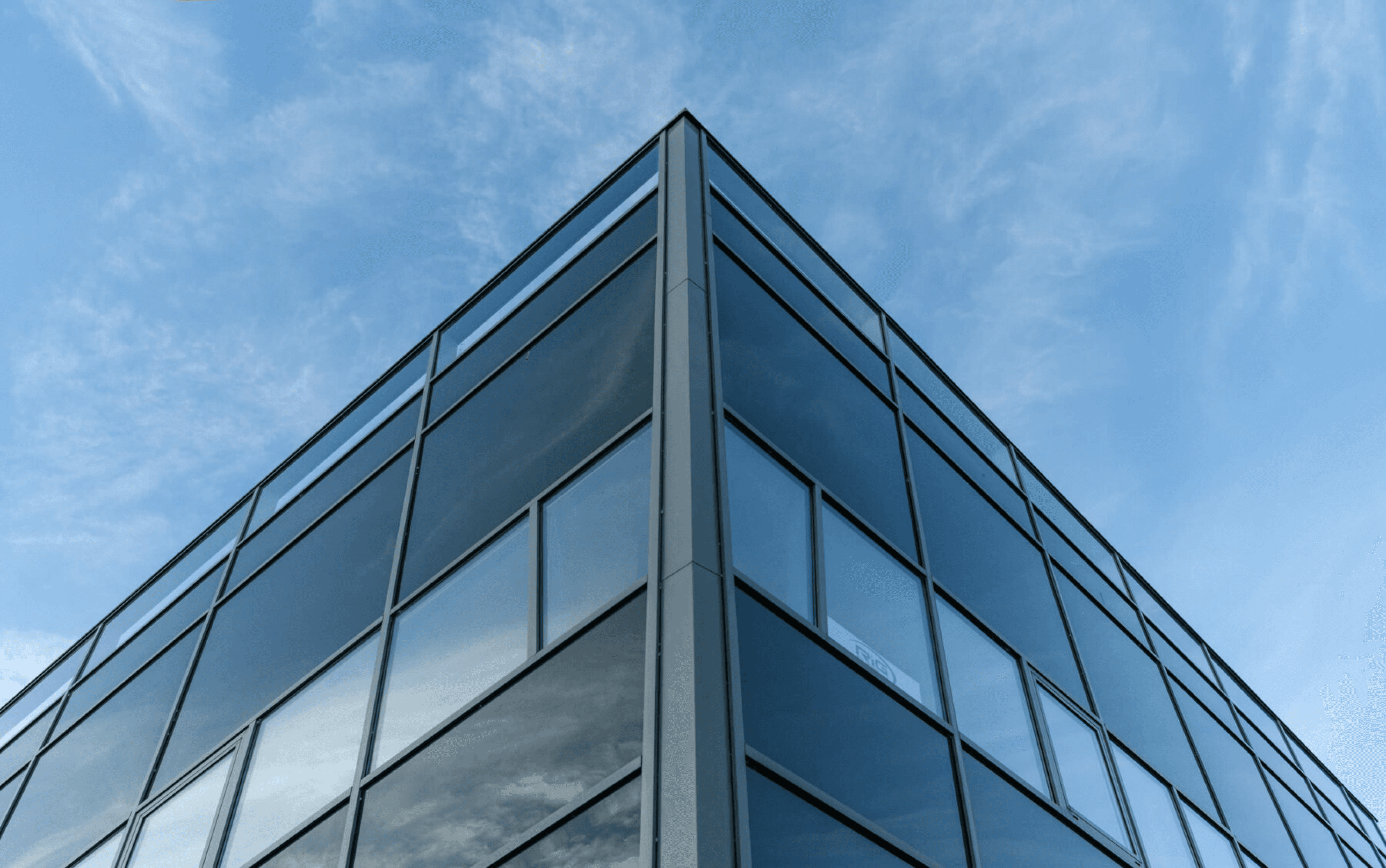 Looking up on a tall building full of windows and a blue sky.