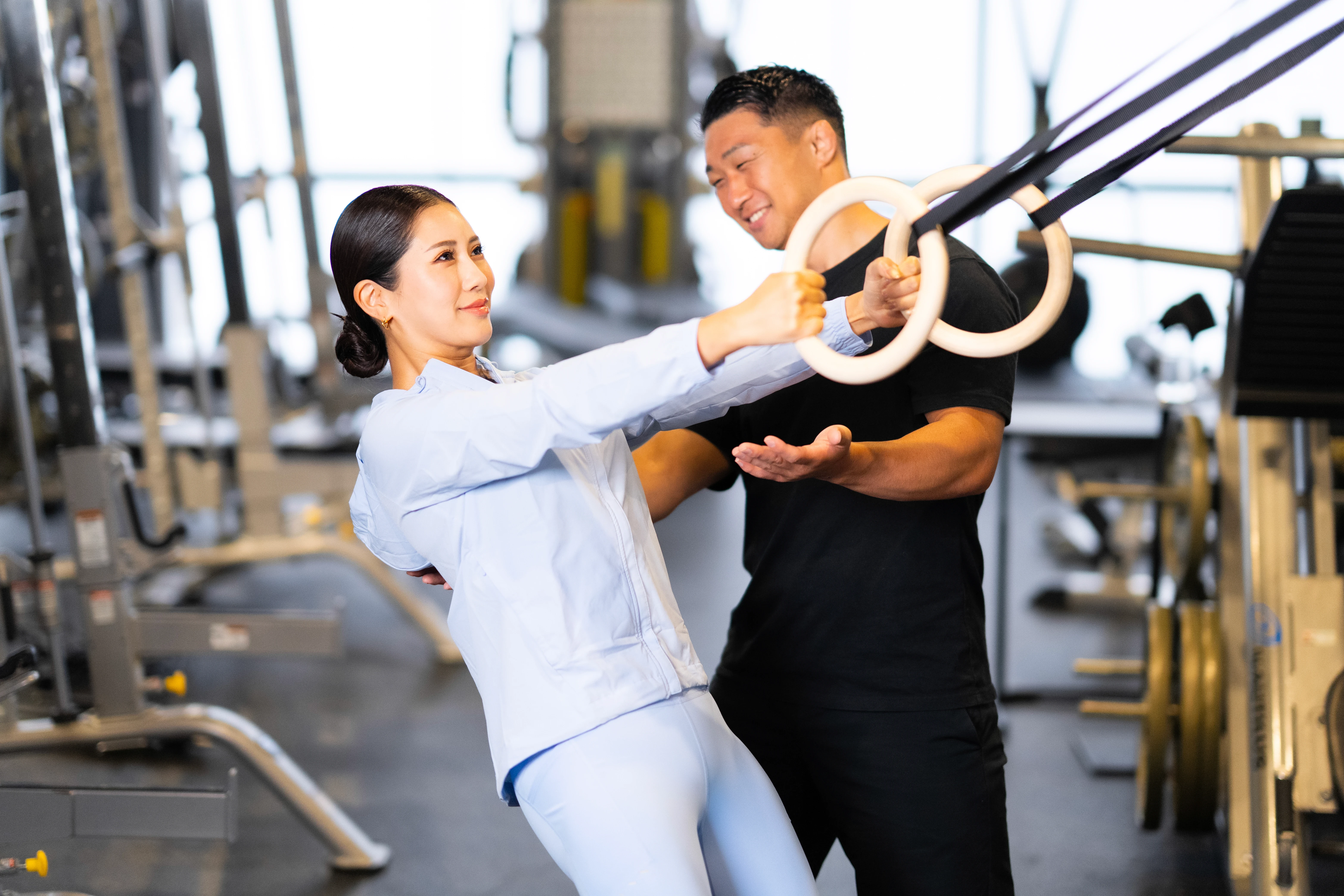 A Body Bento coach crouching beside a client on a weights bench, talking through her daily habits