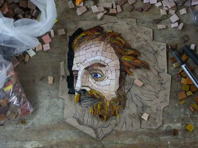 Mosaic art of a bearded man with flowing hair, created with colorful tiles at Mosaiclegs Art Studio.