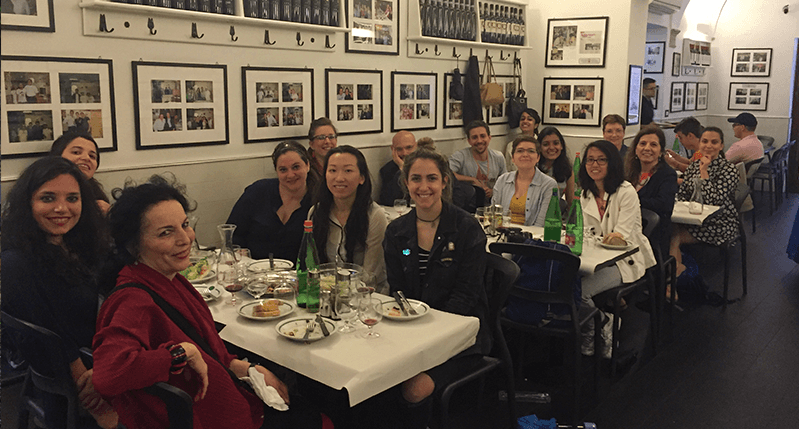 A group of people sitting at a couple of restaurant tables.