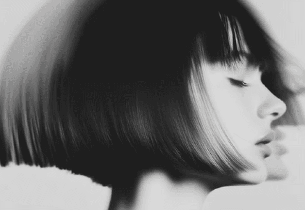 A black and white image of a woman with a short bob haircut, showcasing her profile and expression.