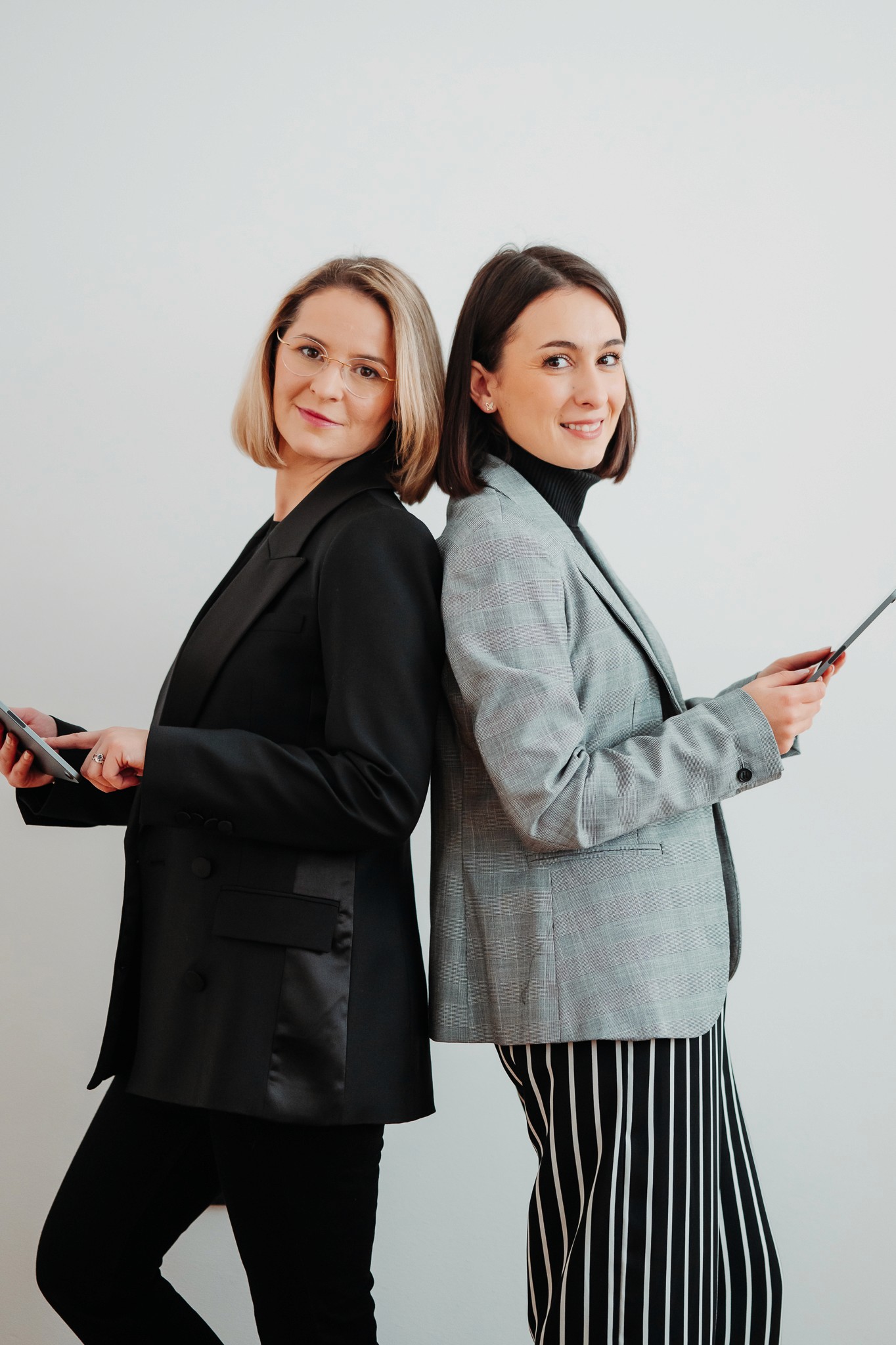 Man wearing headphones and a white t-shirt working on a laptop in soft natural light, with window shadows cast on the wall.