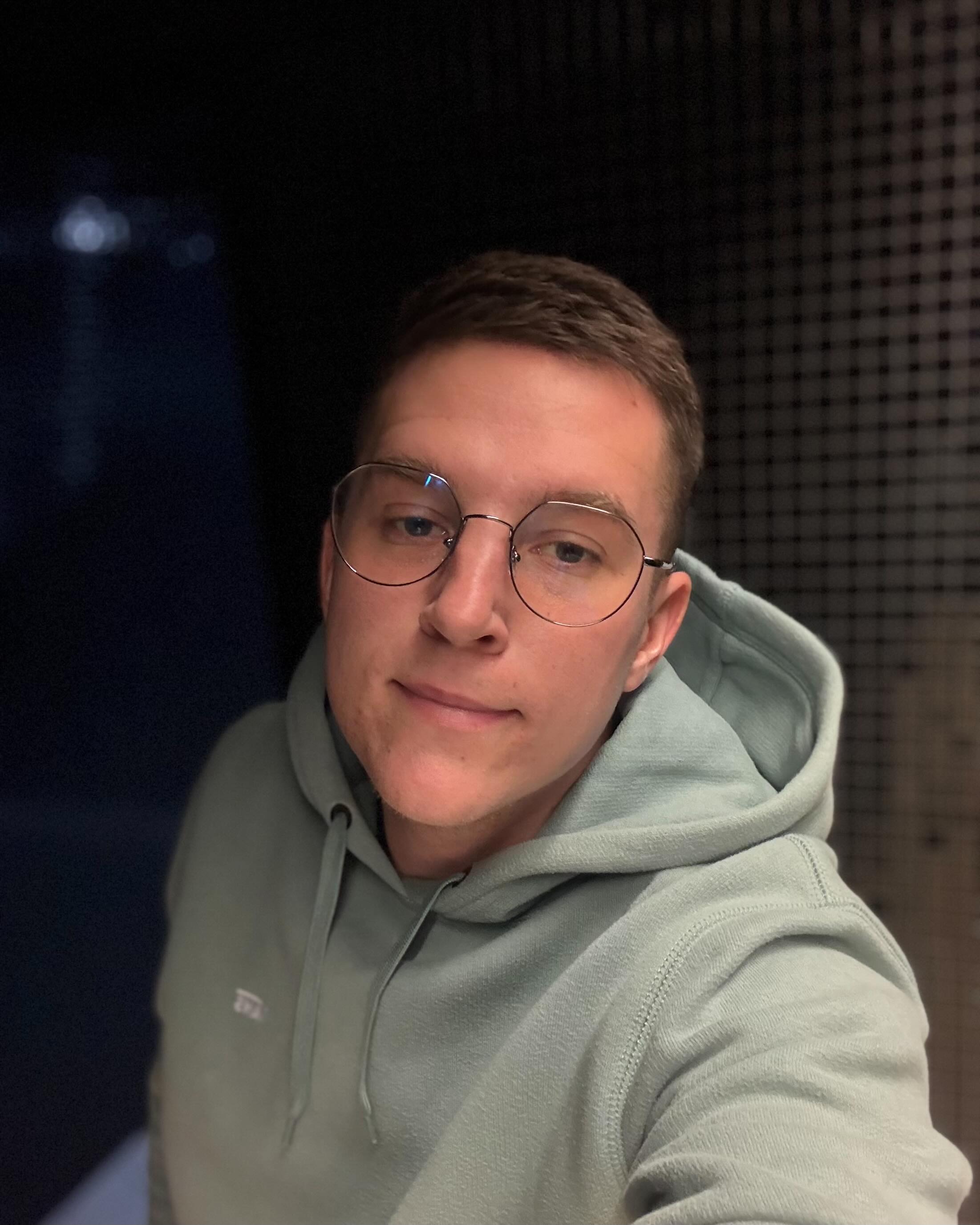 A thoughtful young person with dark hair gazes to the side, captured in soft black and white lighting.