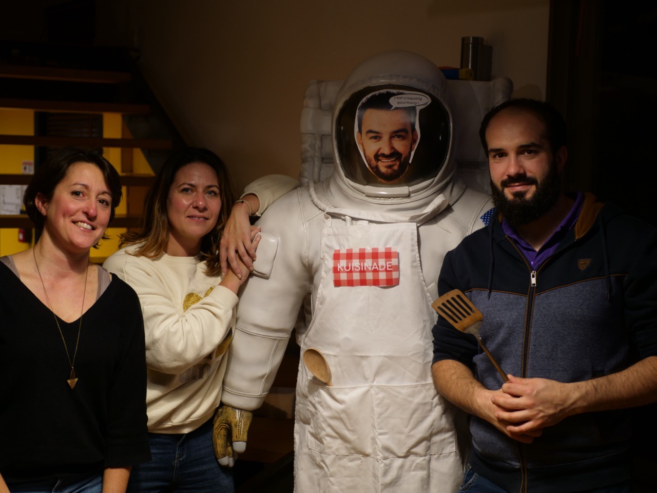 trois personnes qui posent à côté d'une statue d'astronaute