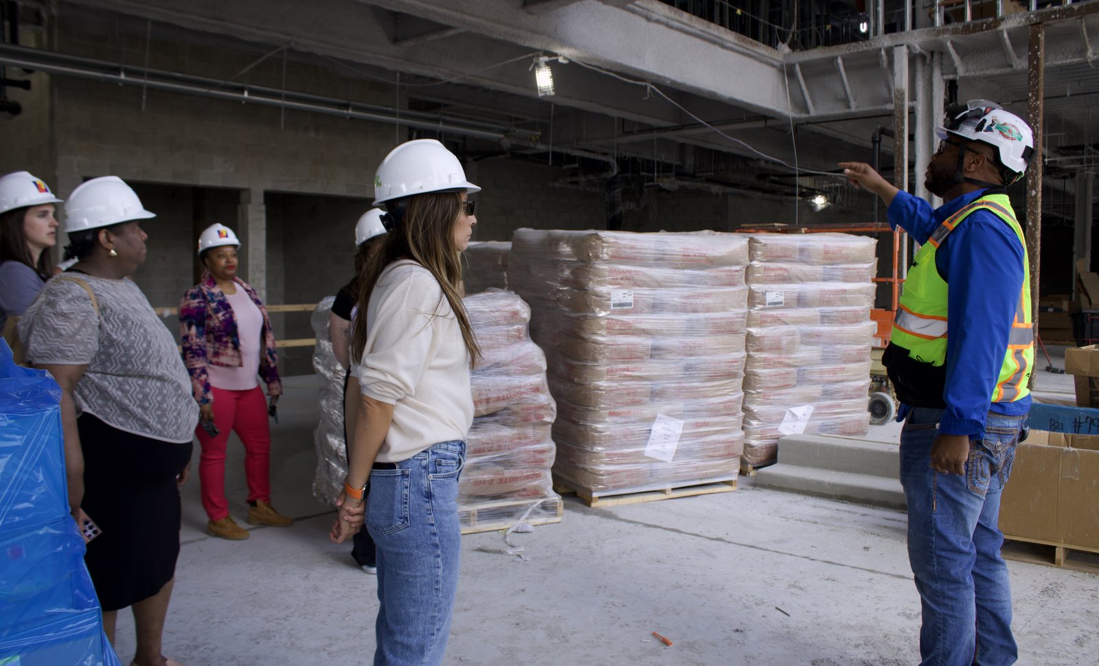 A group in hard hats touring a building under construction