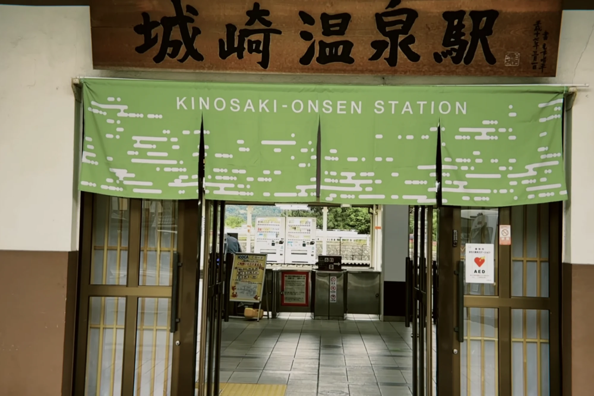 The front of Kinosaki Onsen Station with its green noren and clock.