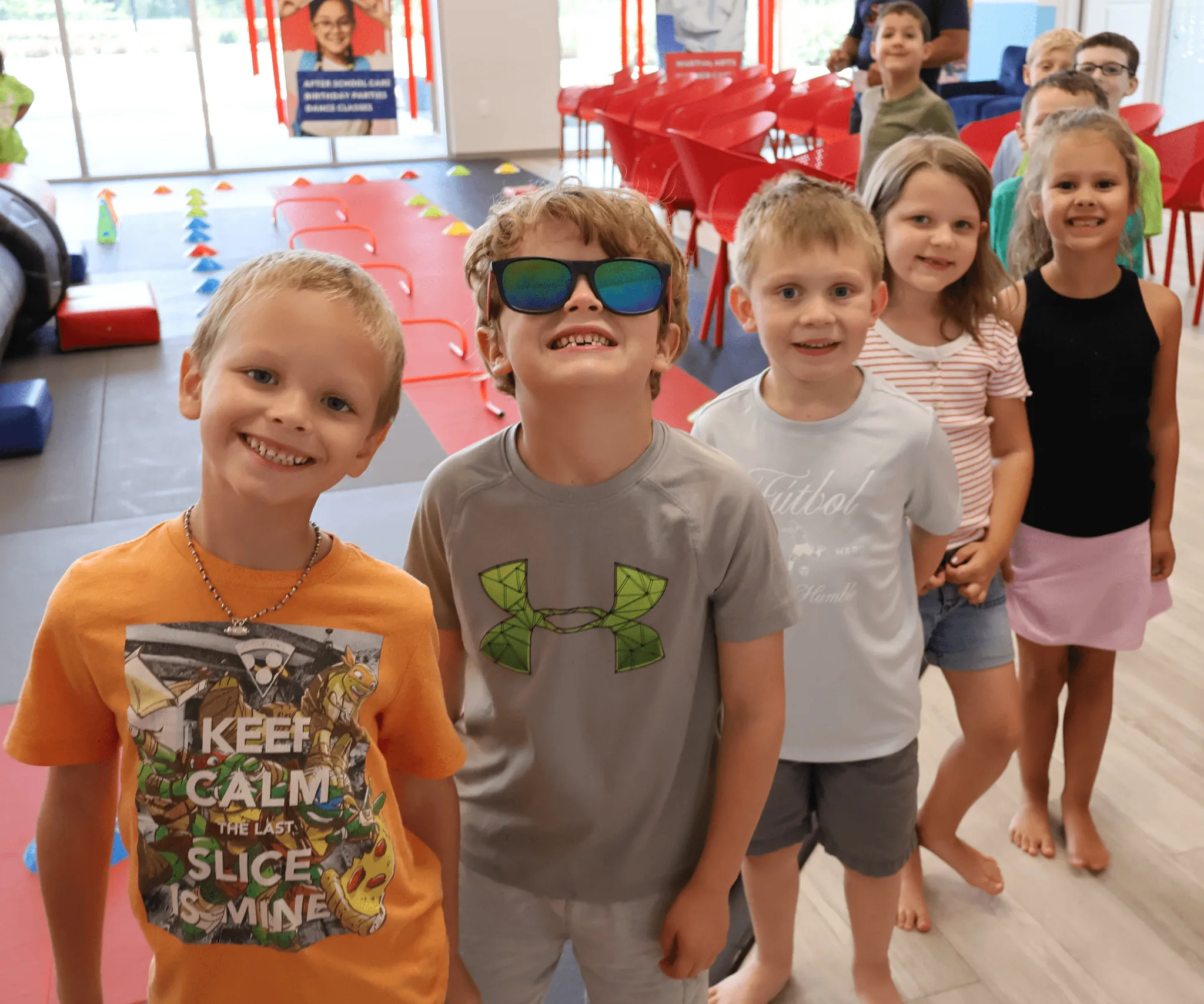 Group of Kids in line in front of the martial arts mat smiling for the picture 