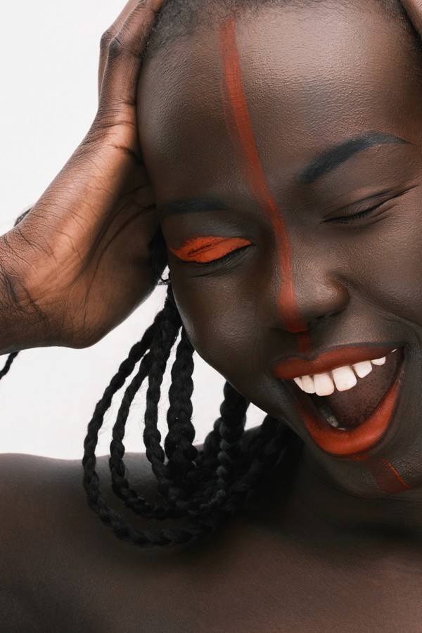 Joyful close beauty portrait with braids and vivid orange makeup