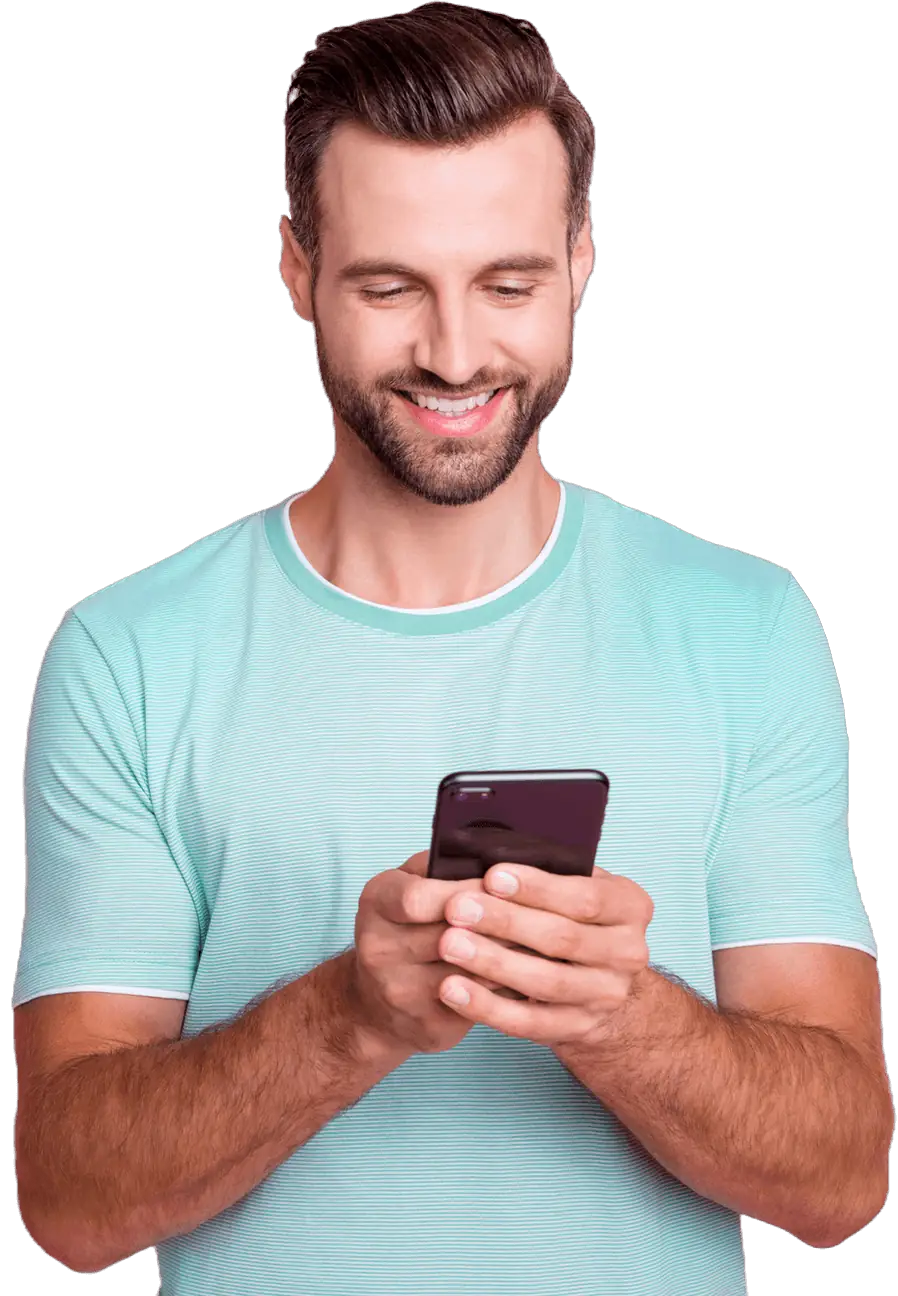 A smiling man holds his cell phone, looking cheerful and engaged.