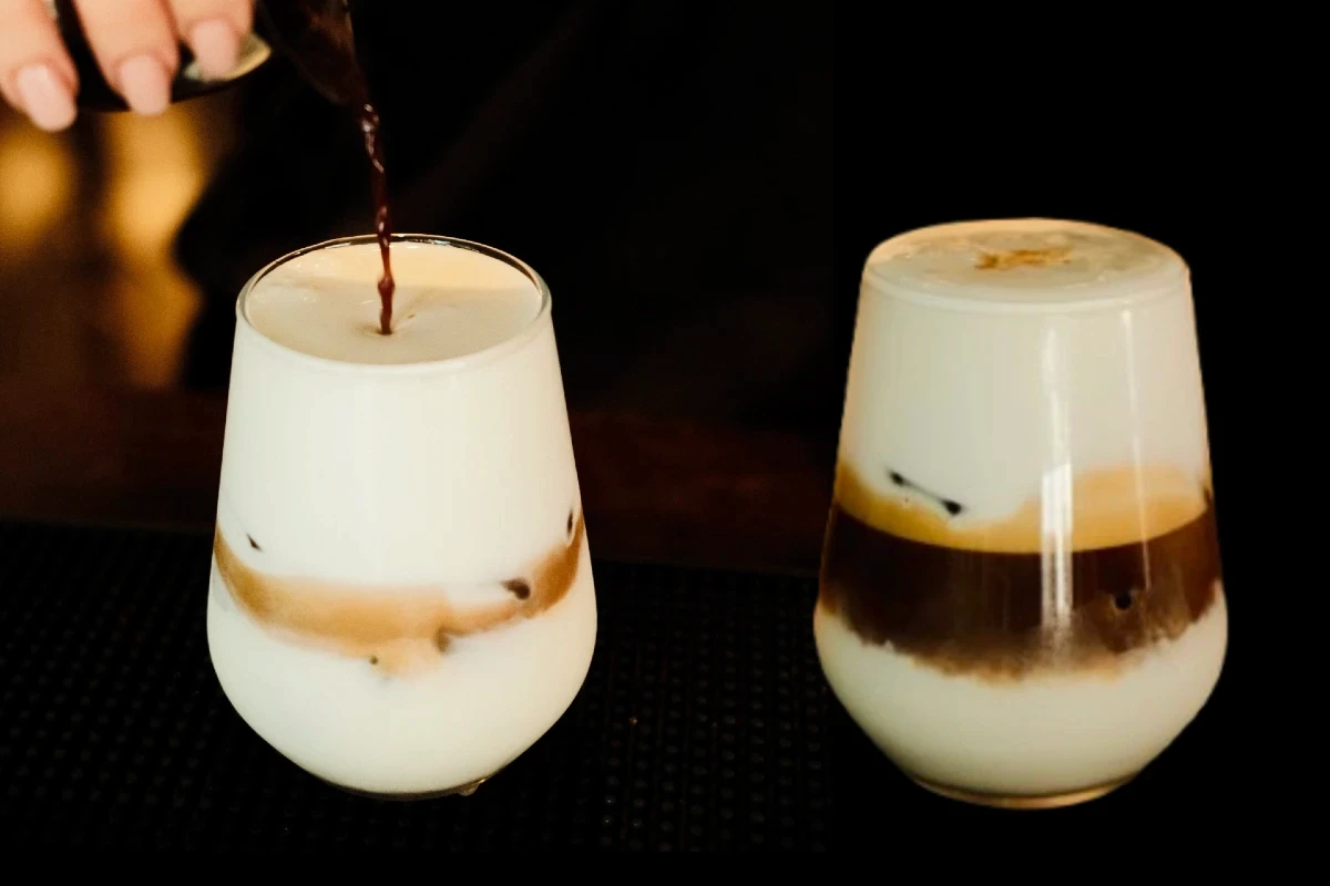 צילום מוצר אמנותי של קפה קר בשכבות על רקע שחור דרמטי. הקומפוזיציה מציגה את רגע מזיגת האספרסו לתוך החלב לצד כוס מוכנה, מאת Shiriz Photography הצלמת שירי עציץ.