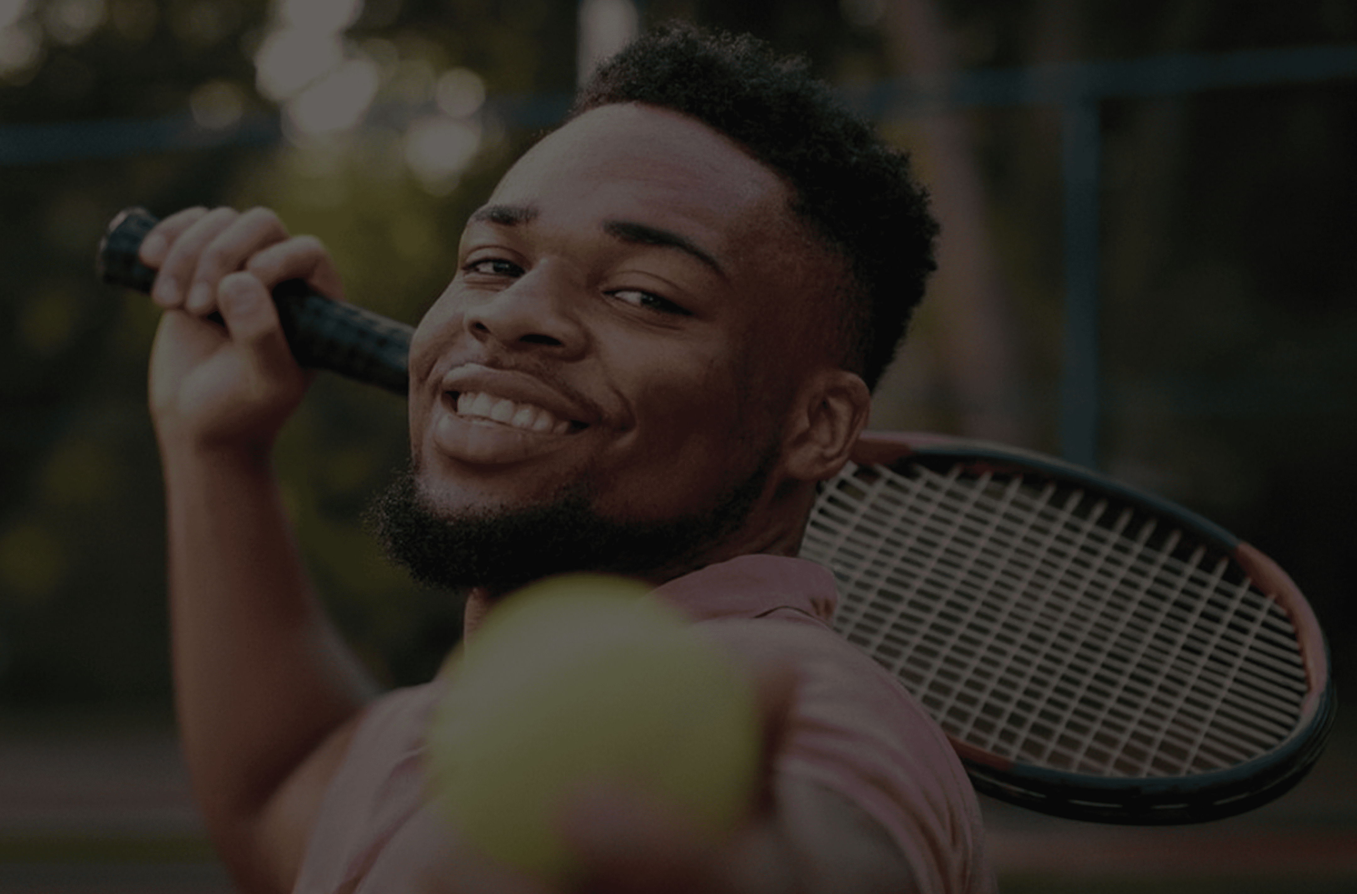 Smiling African American tennis player holding a tennis racket and ball, ready to serve.
