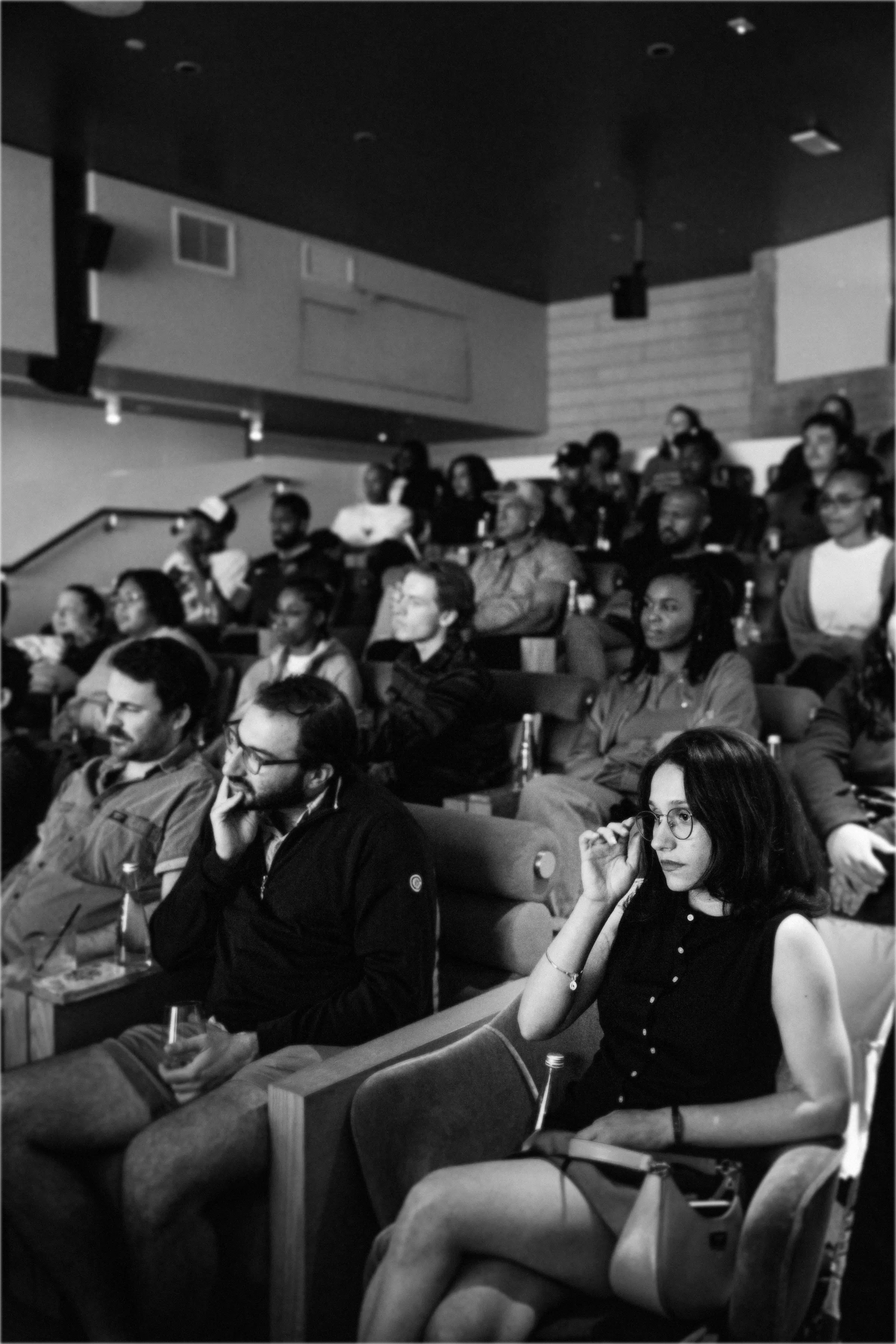 A black and white image of people watching a movie in a theater.