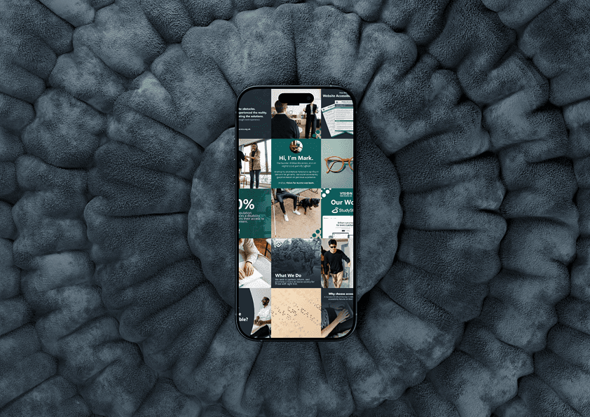 An image mockup of a phone, with social media graphic designs for Vision For Access CIC, on a dark blue, ruffled pillow background.