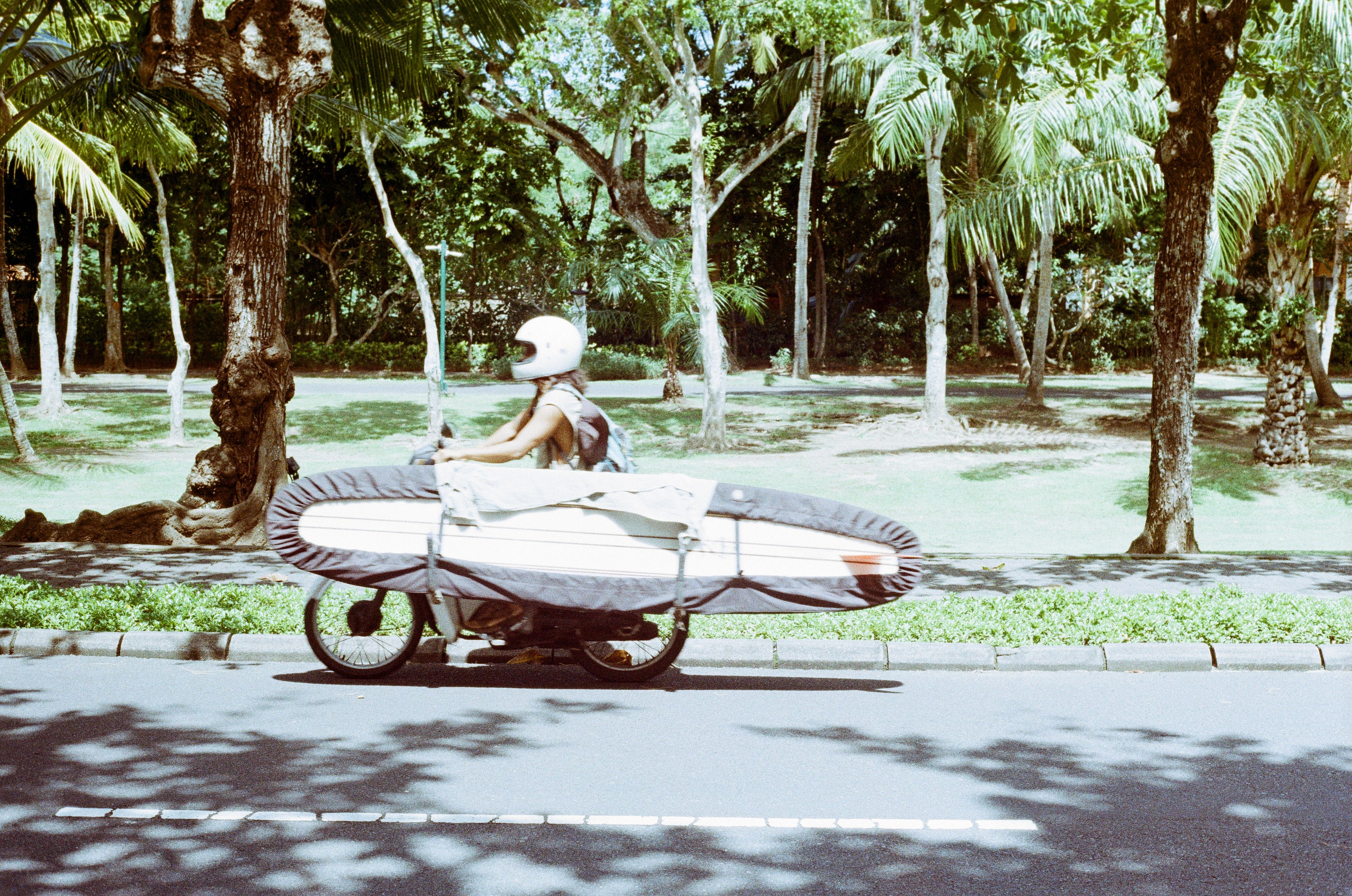 longboard surfer is driving on his bike in Bali, Uluwatu