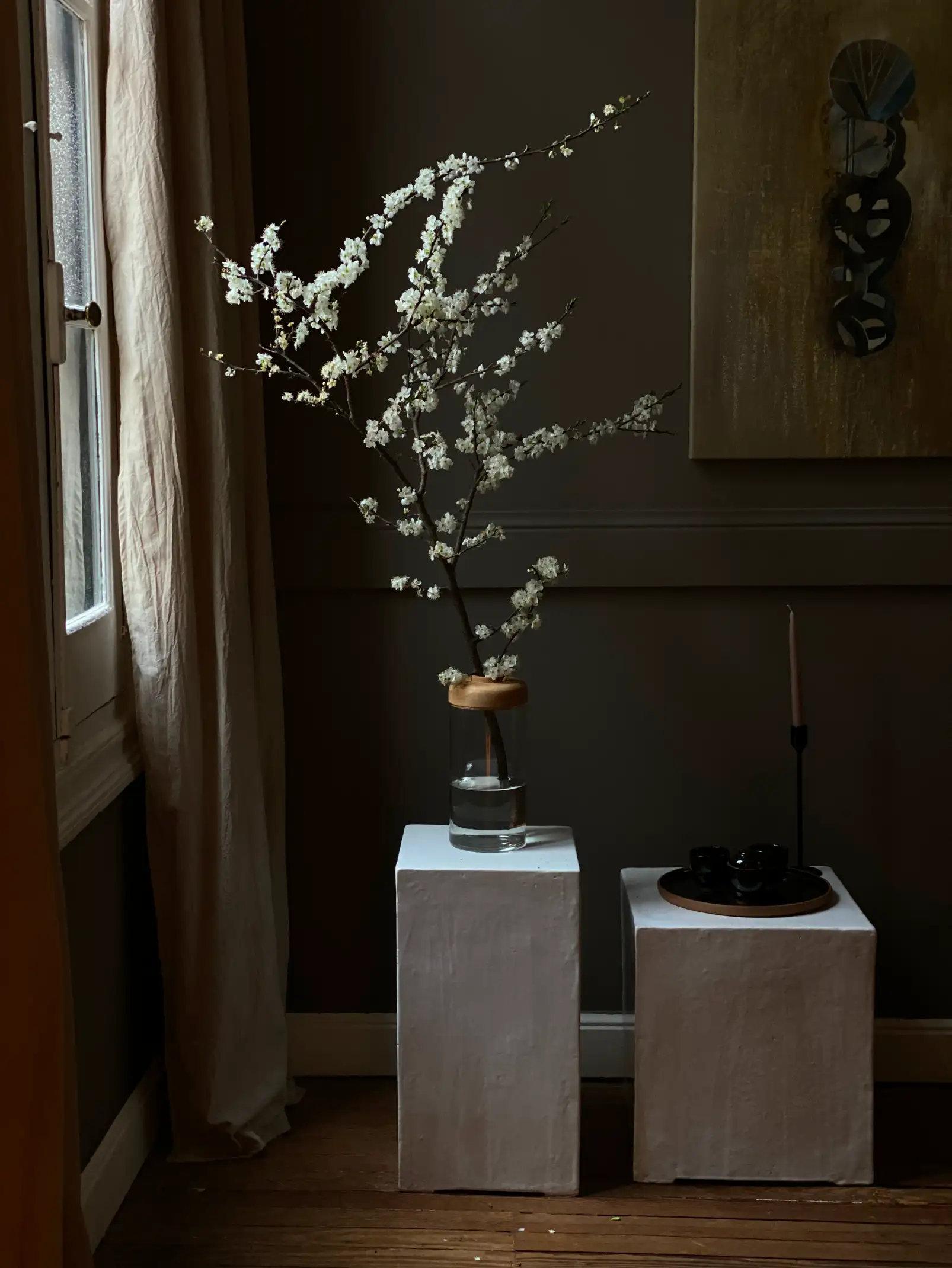 Arreglo floral con ramas blancas sobre pedestales para interioristas que valoran el equilibrio entre arte floral y estética minimalista.