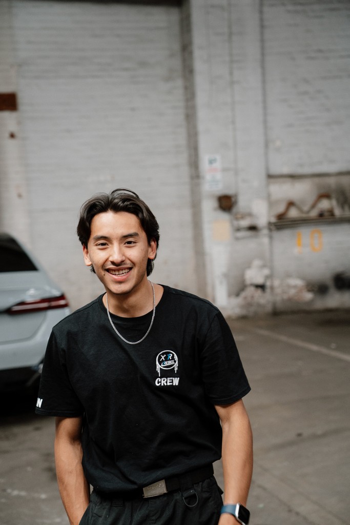 Silhouetted band members play instruments in a smoky warehouse, backlit by vibrant orange and teal lights, creating a moody, dramatic ambiance.