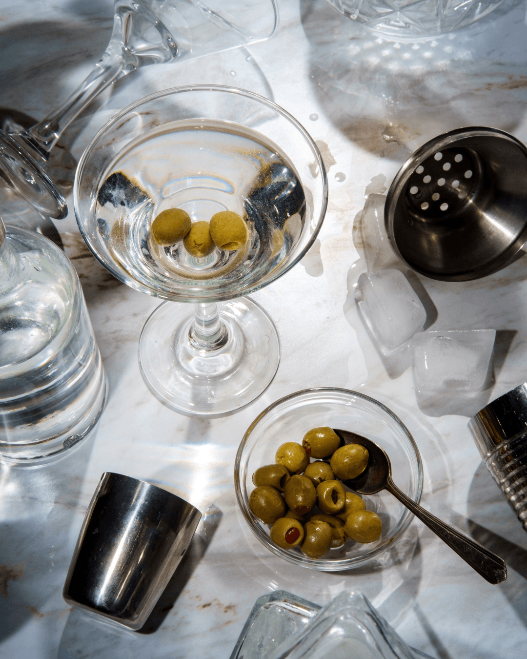 A person in a trench coat and chunky black shoes stands on a park path in autumn