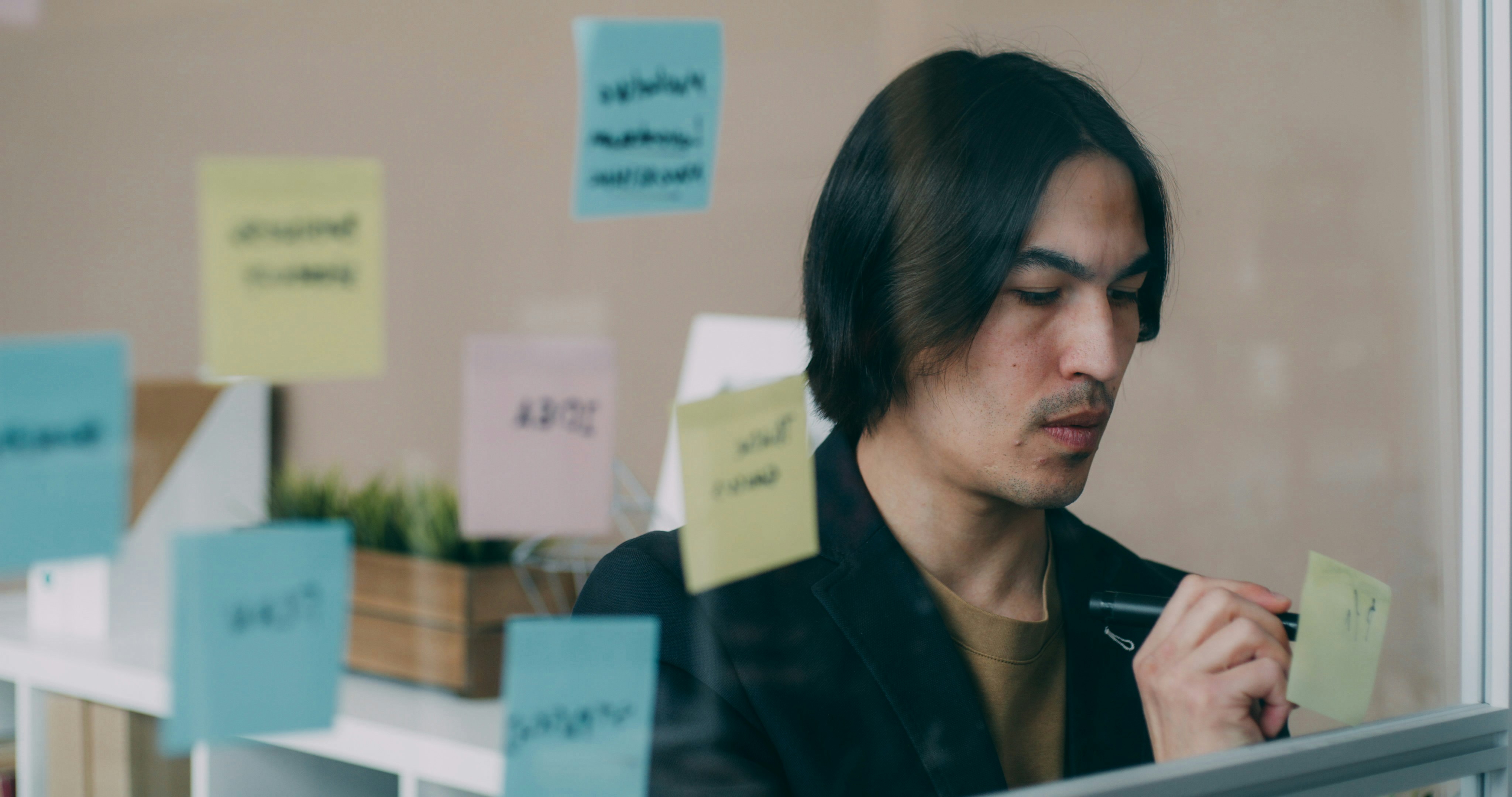 A man sitting in front of a window covered in sticky notes