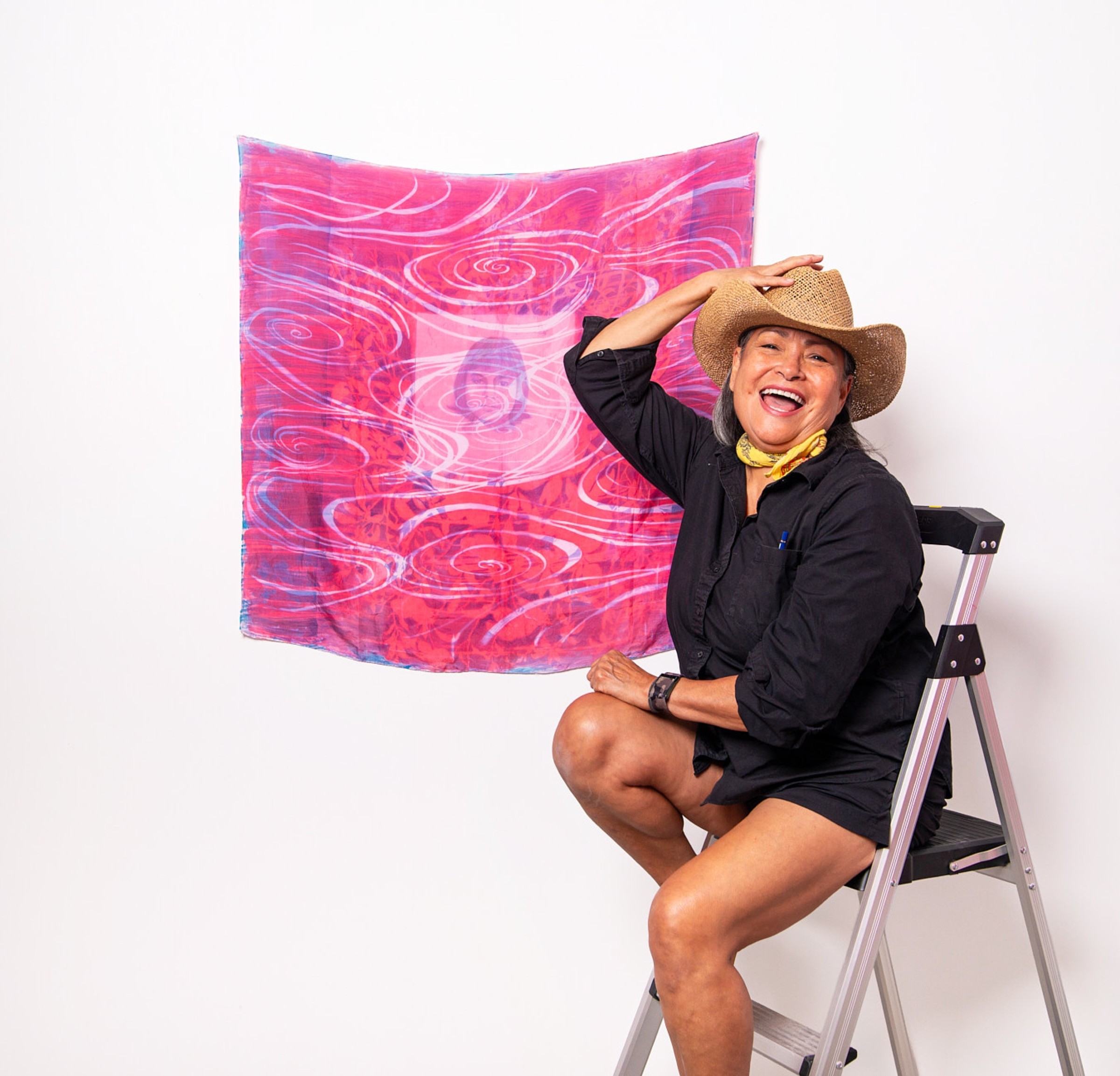 Artist portrait beside a colorful textile artwork