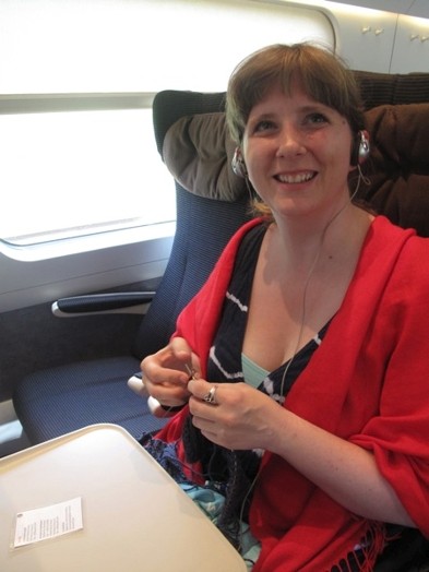 A photo of a woman listening something at headsets while sitting in a bullet train.
