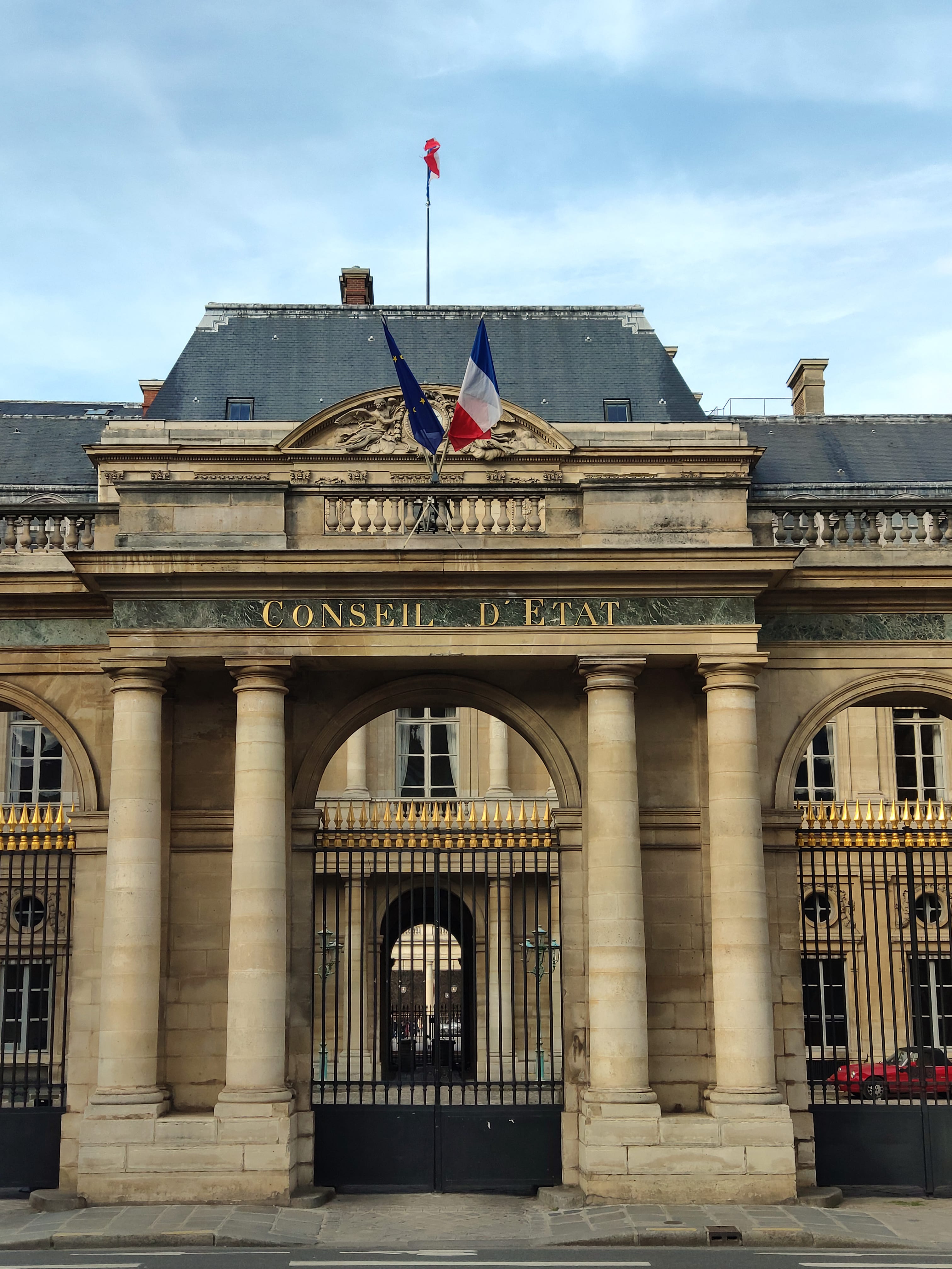 The facade of an institutional building with French flags.