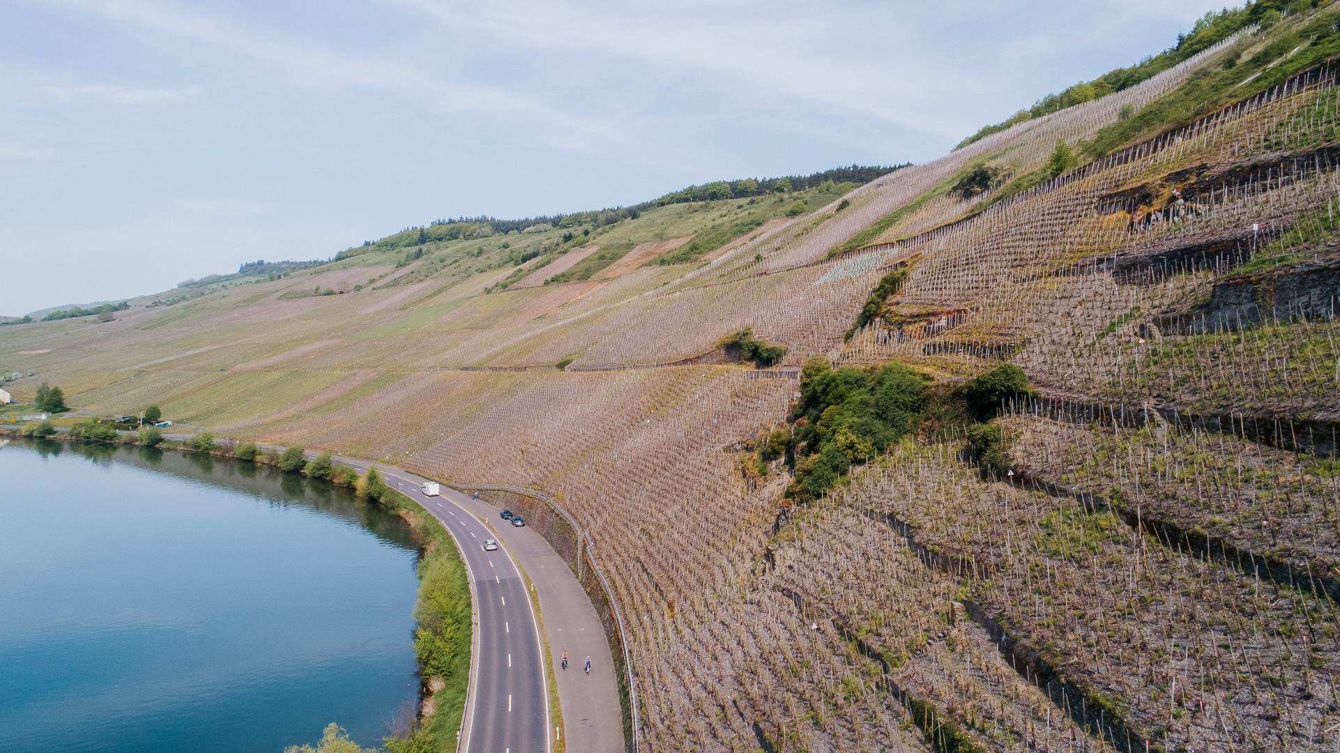 A picturesque view of a winding river flanked by rolling hills and rock formations, beneath a bright blue sky.