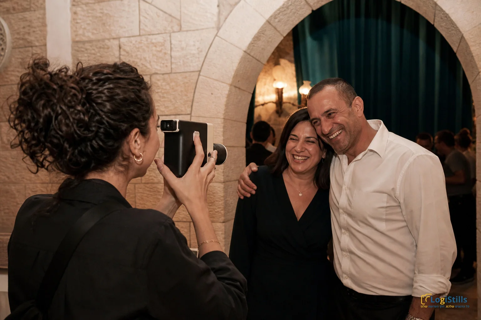 צלמת מצלמת זוג אורחים במצלמת אינסטנט באולם אבן