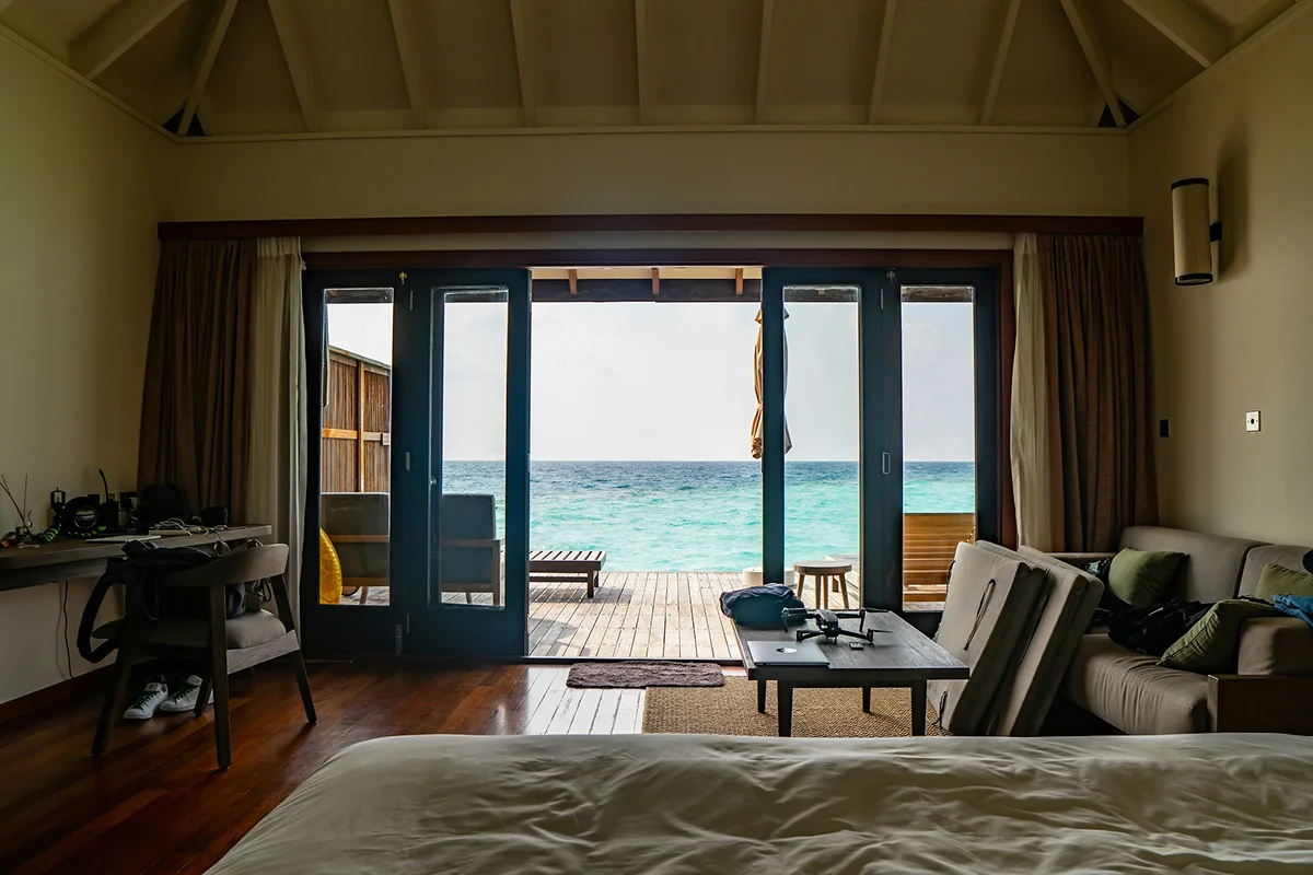 Deluxe sea view room with large glass doors opening to a private deck and turquoise ocean view.