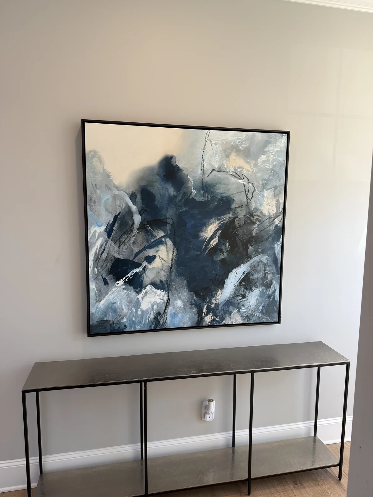 Large blue abstract artwork installed above a narrow console on a light wall.