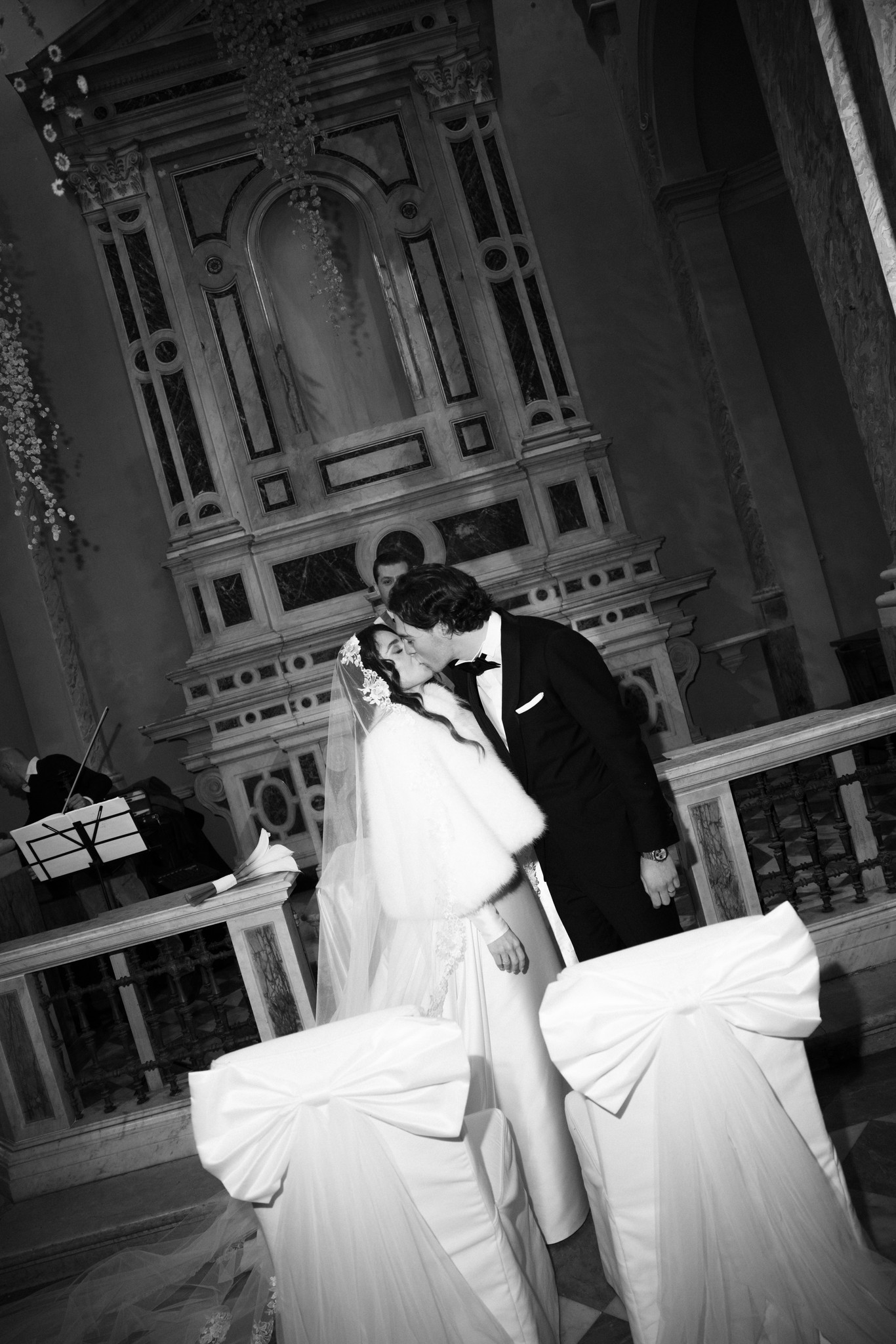 Sposi si baciano davanti alla porta affrescata del Circolo di Lettura a Parma, velo svolazzante, reportage matrimoniale