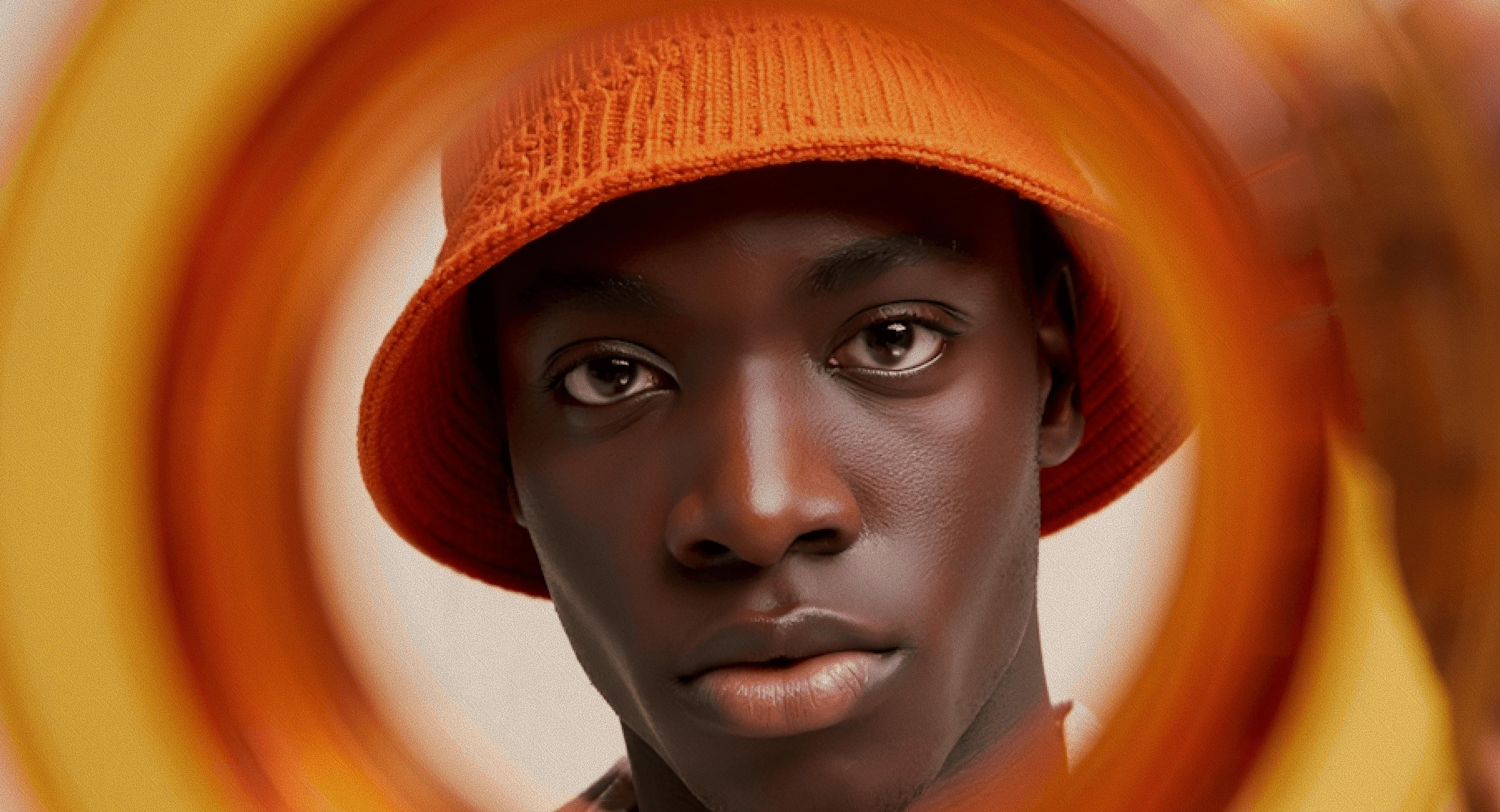 Portrait of a man in an orange bucket hat framed by circular blurred patterns