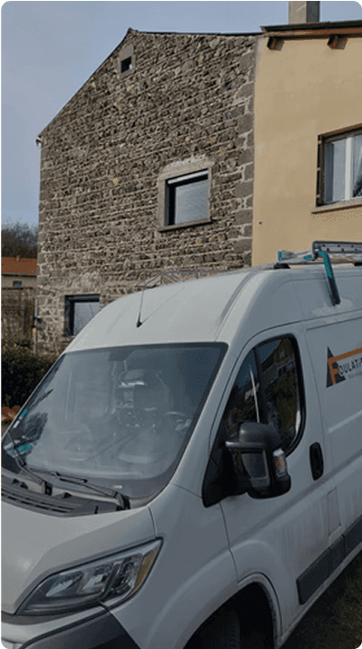 Camion blanc de chantier devant une maison en pierre