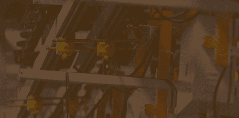 A man in a brown blazer and a woman in a light sweater sit at a desk with a laptop, discussing something. The room is dimly lit, creating a focused atmosphere.