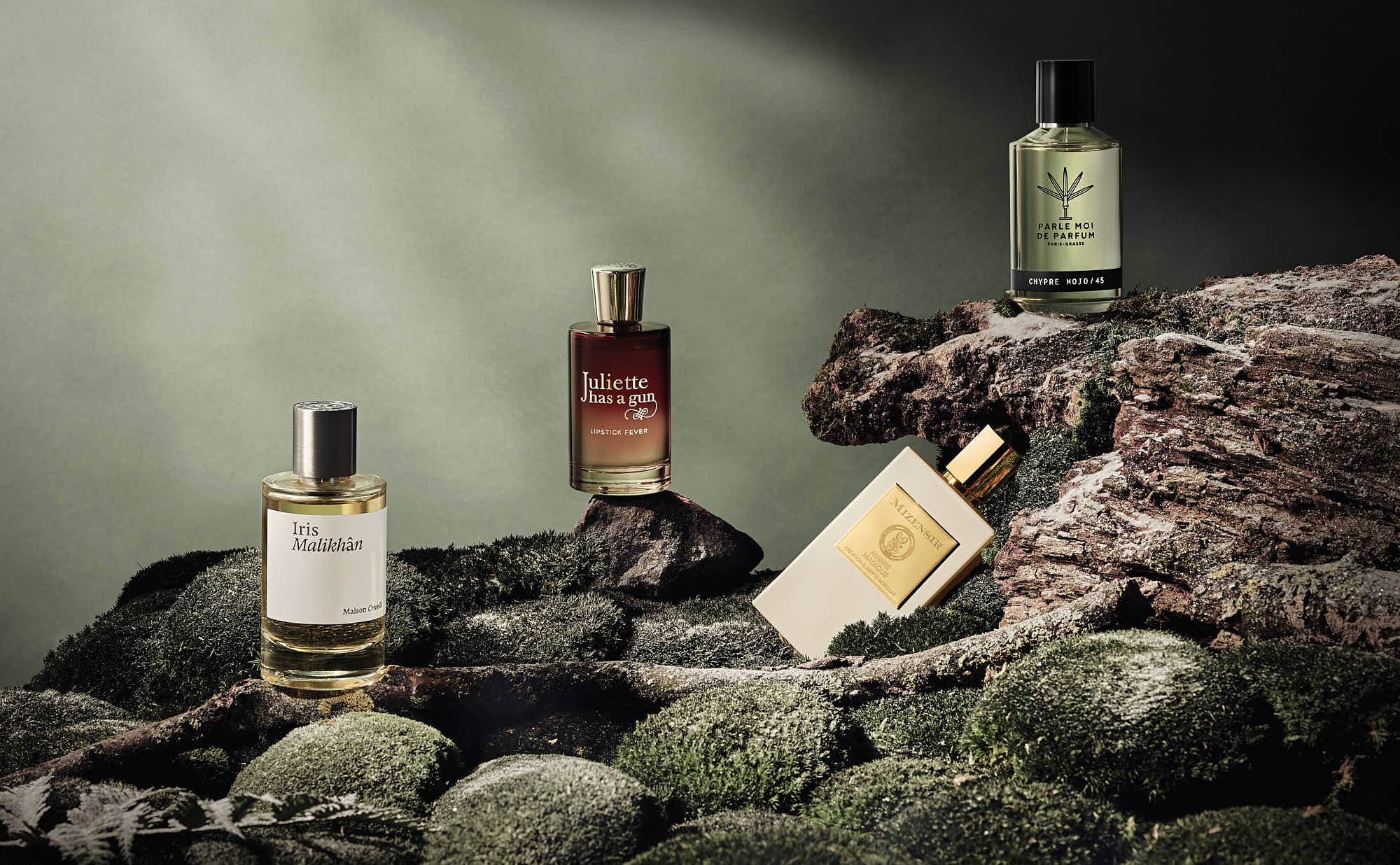 Three perfume bottles placed on rocks, illuminated by soft light, creating an elegant and calming atmosphere.