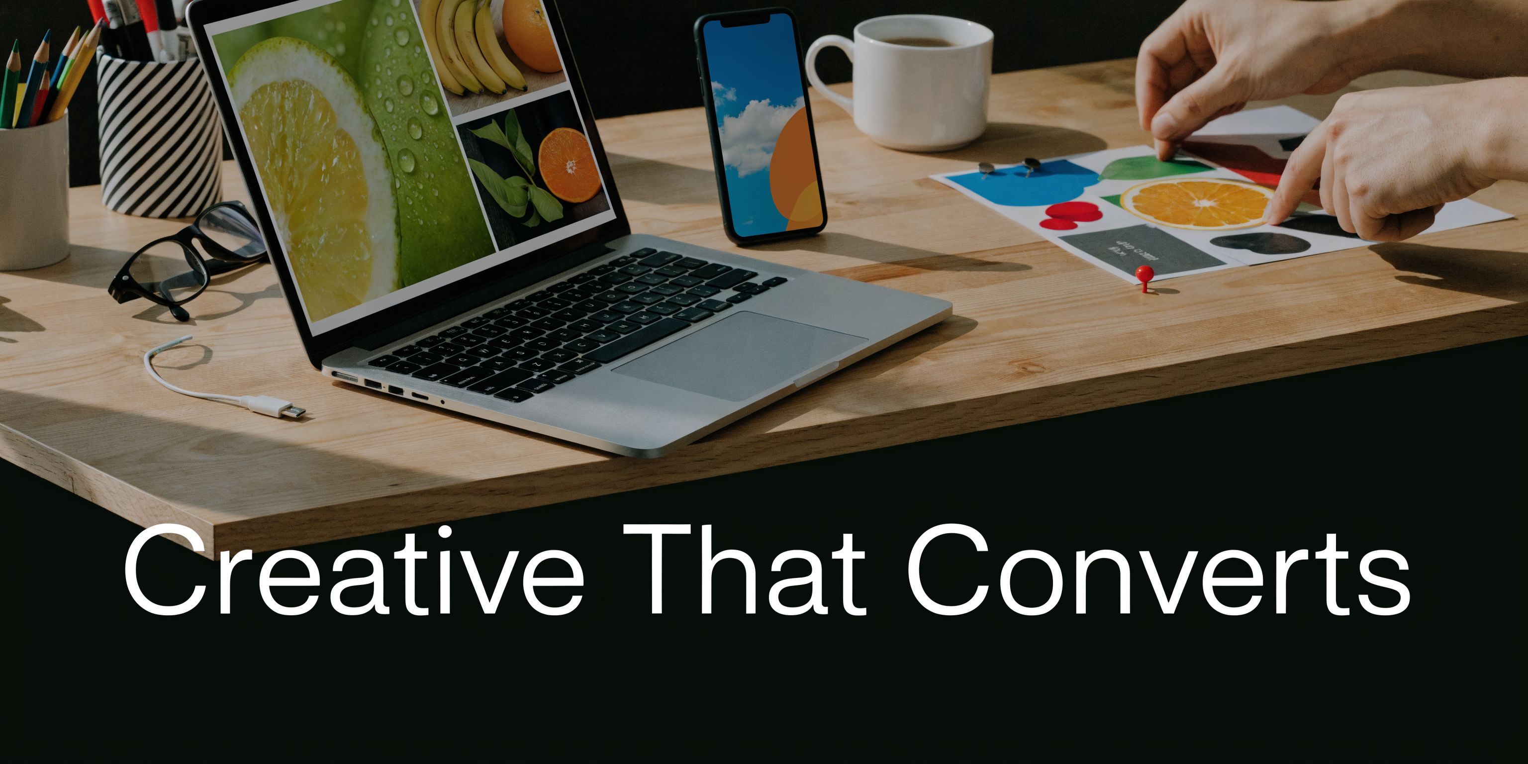 A professional designer working at a wooden desk with a laptop, smartphone, and creative mood board.