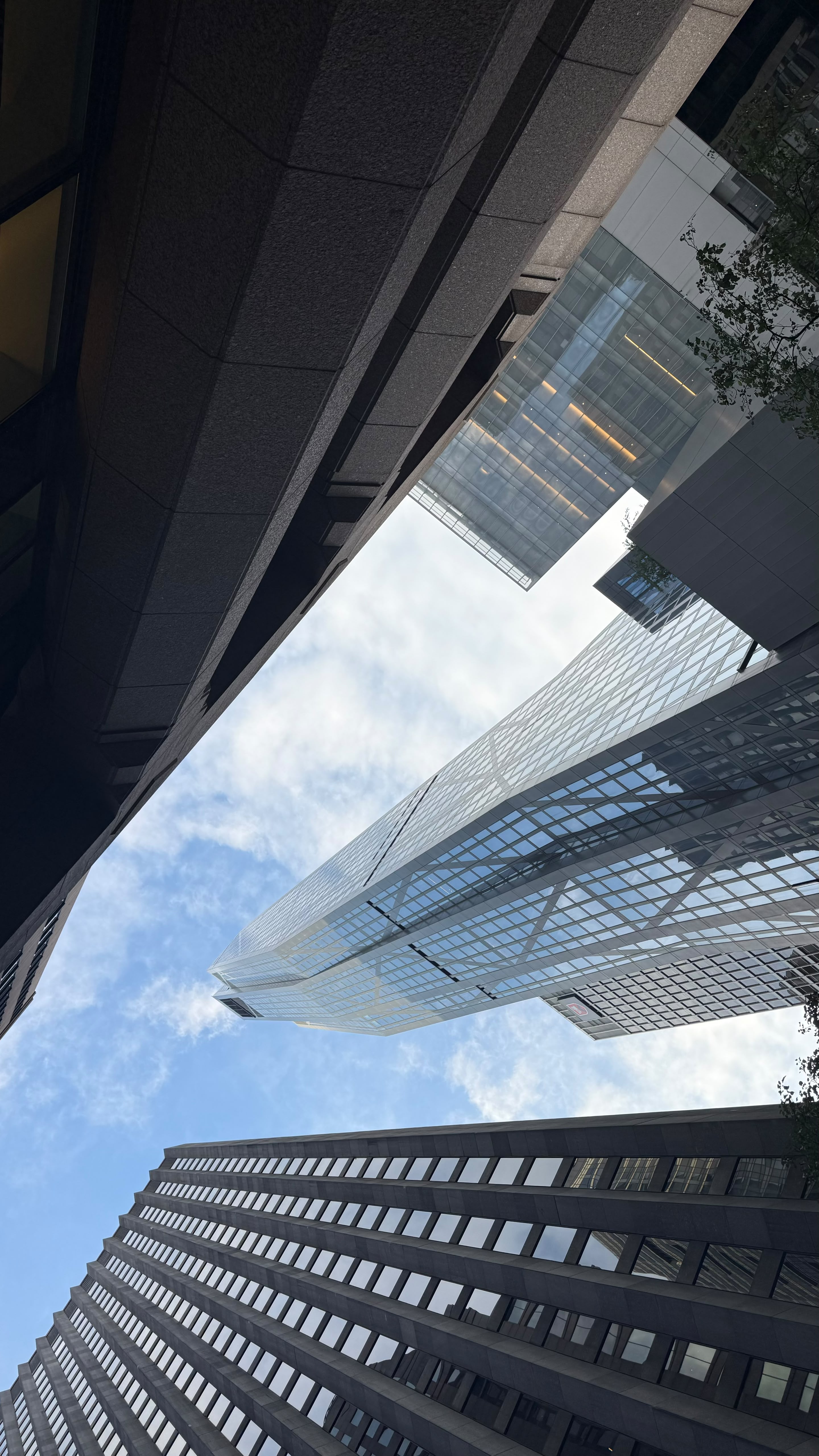 Low-angle view of glass office towers converging toward the sky.