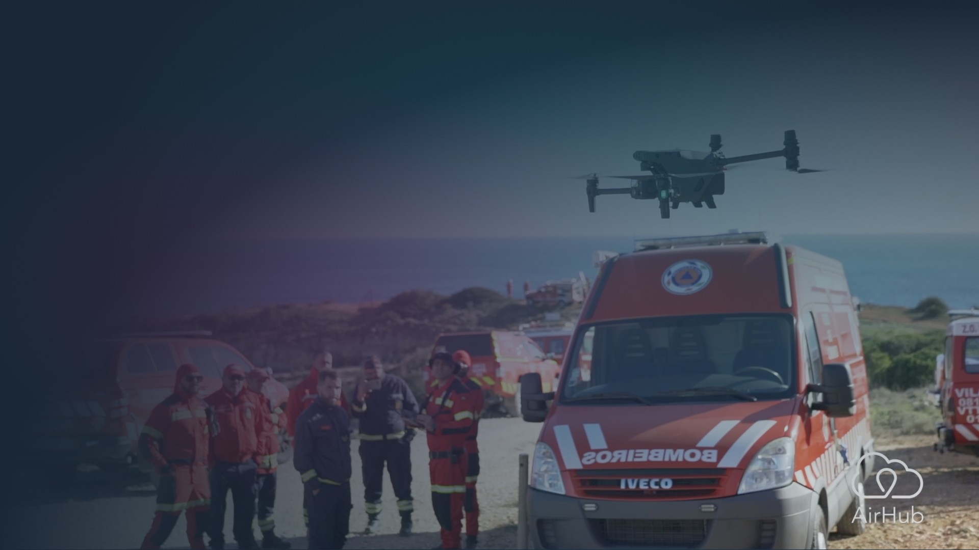 A drone flies above a group of firefighters and emergency response vehicles during an outdoor operation, supported by AirHub drone management software.