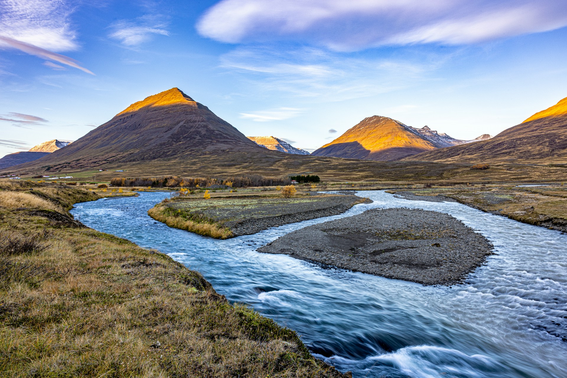 Mountain landscape with a winding river in Iceland's Westfjords during golden hour.