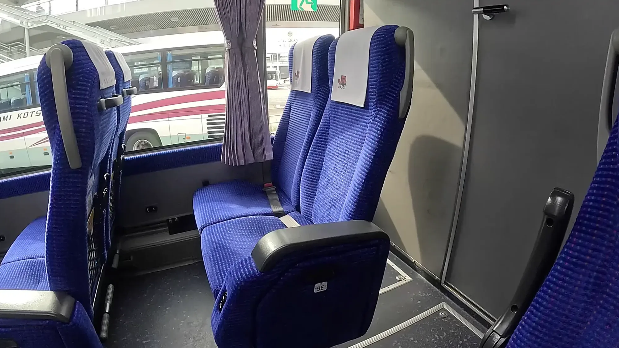 The interior of a highway coach to Kurokawa Onsen, reserved seats and a red Sanko coach through the window