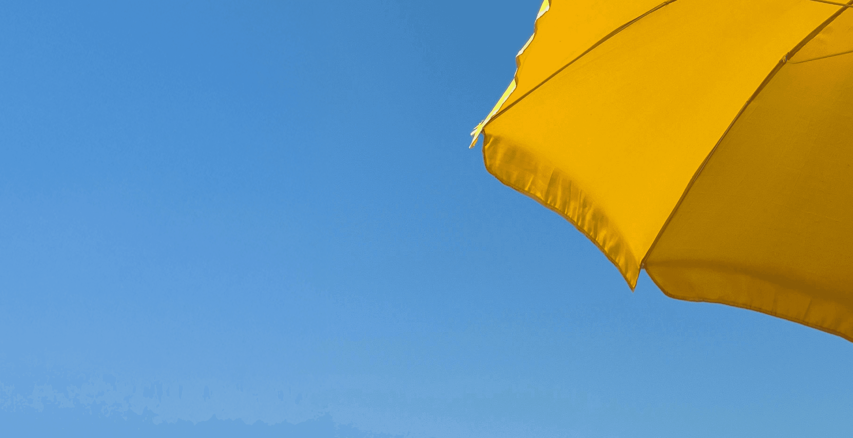 A bright yellow umbrella set against a clear blue sky, capturing a sunny and cheerful scene.