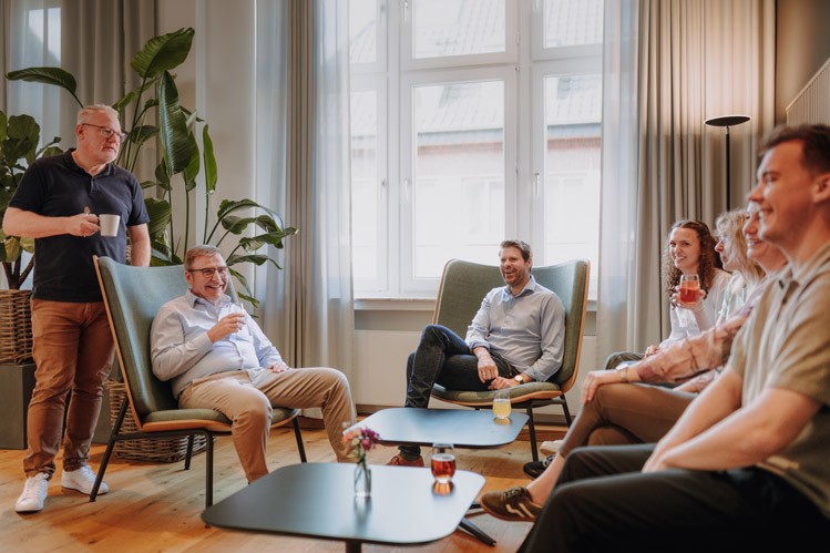 Beratungssituation bei SLB: Drei Personen sitzen in einem gemütlichen Besprechungsbereich mit Sesseln und Couchtisch.