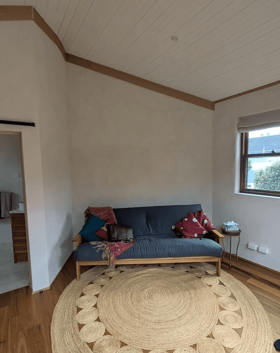 A photo of the interior of this hempcrete block house showing a sofa and carpet.